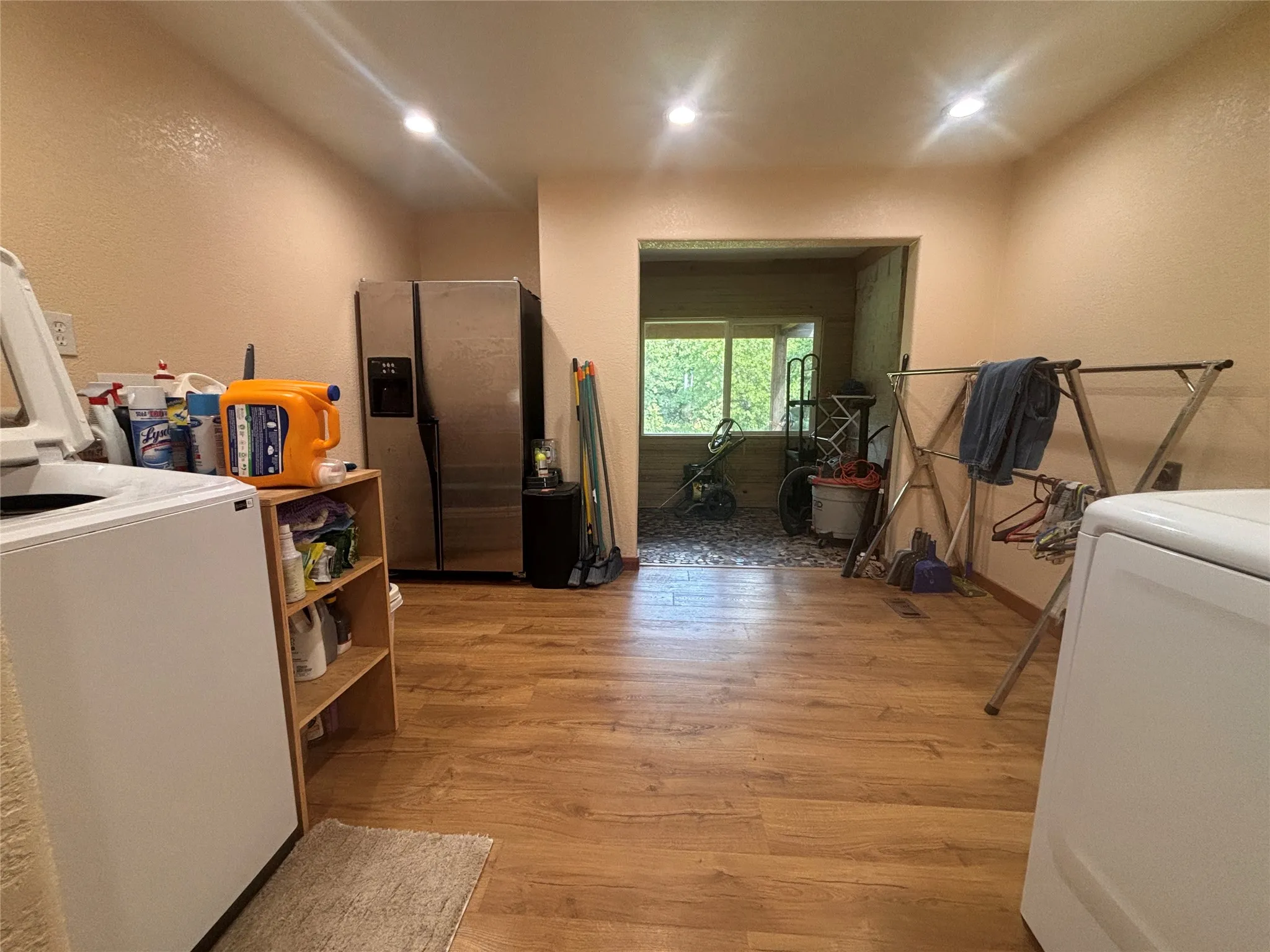 Spacious utility room featuring wood-finish flooring, recessed lighting, and an expansive window in the adjacent area