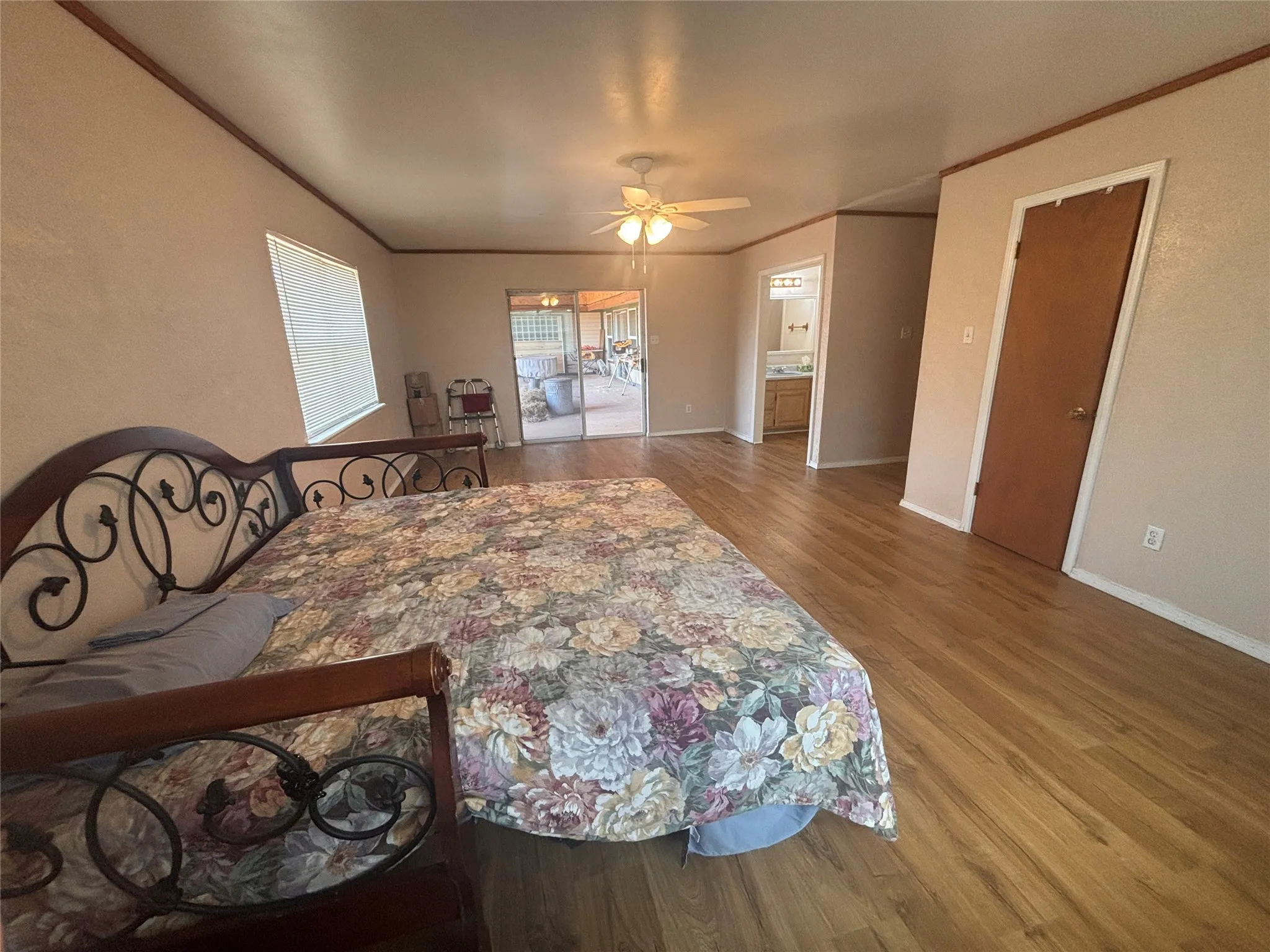 Spacious room featuring wood-finish flooring, a ceiling fan, and direct access to an outdoor patio through sliding glass doors