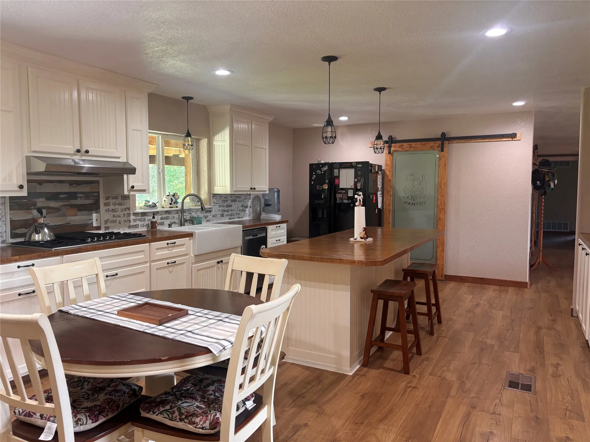 Kitchen featuring wood-finish flooring, white cabinetry, a farmhouse sink, and a sliding barn door