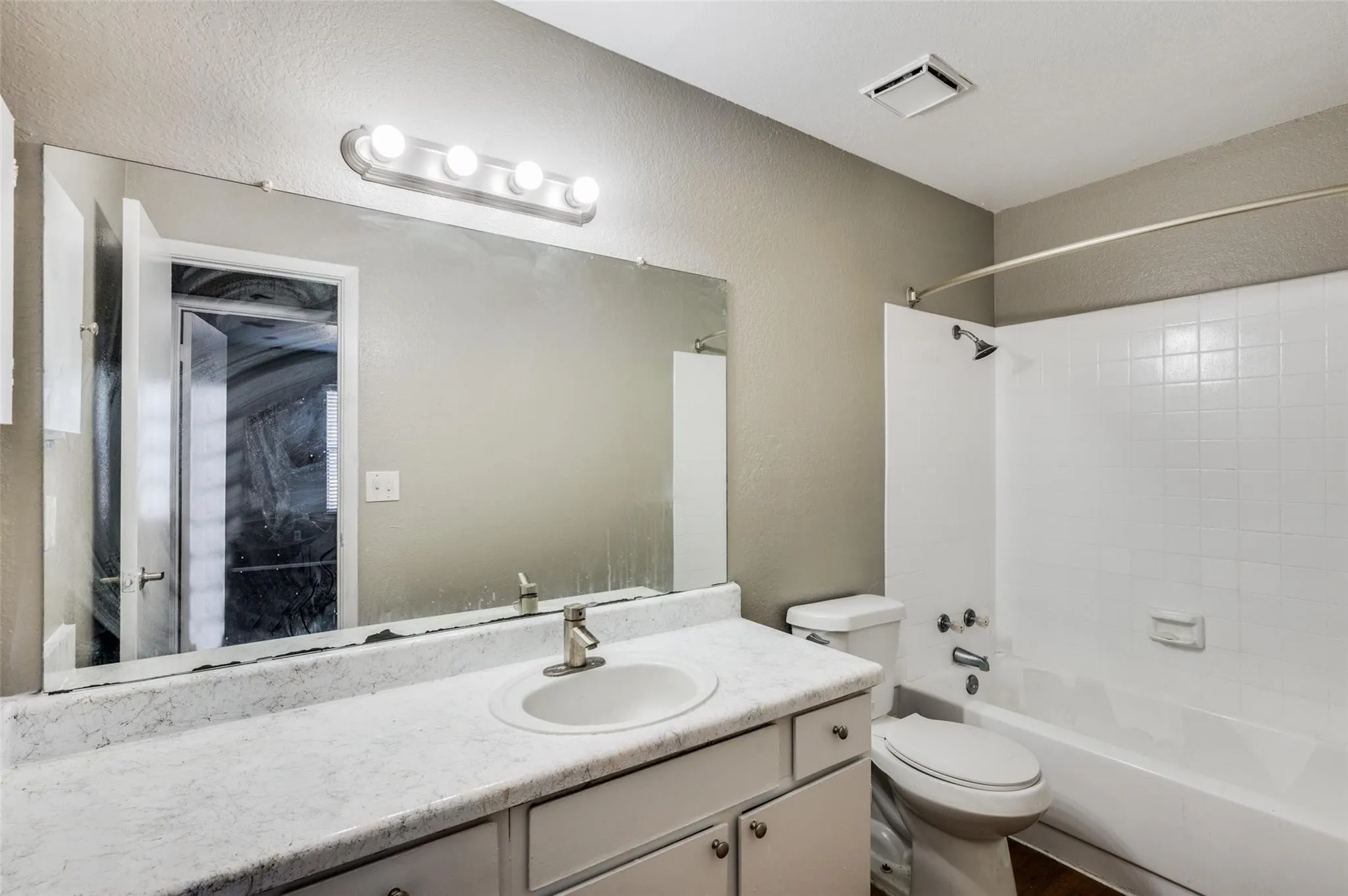 Bathroom featuring vanity,  shower combination, and a textured wall