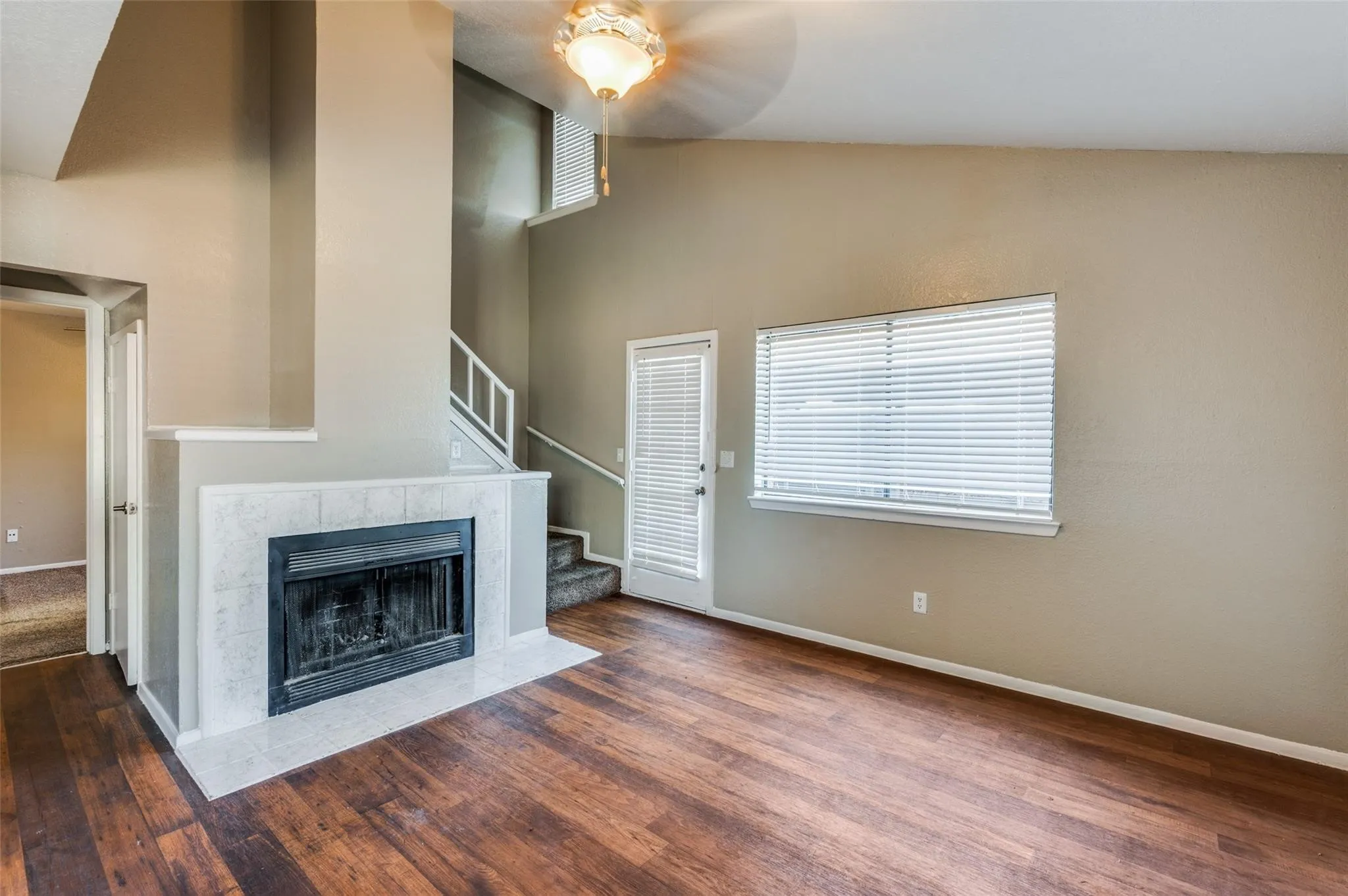 Unfurnished living room with vaulted ceiling, dark wood-type flooring, and a tiled fireplace