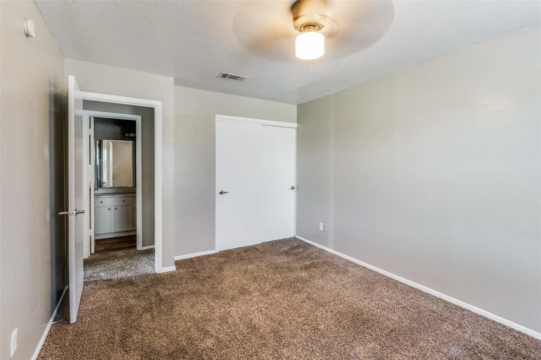 Unfurnished bedroom featuring dark colored carpet, a closet, and ceiling fan