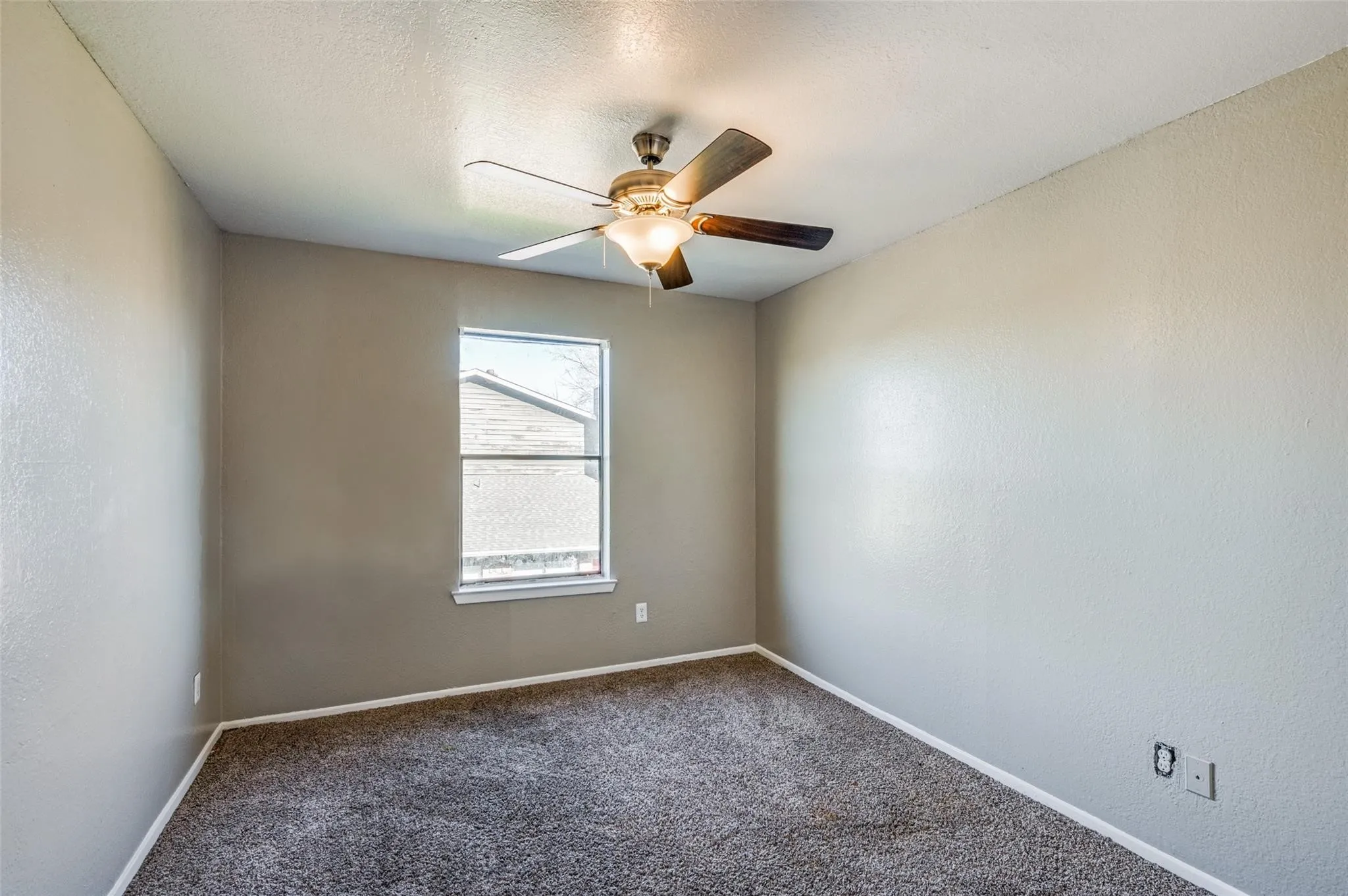 Empty room with dark colored carpet, ceiling fan, and a textured wall