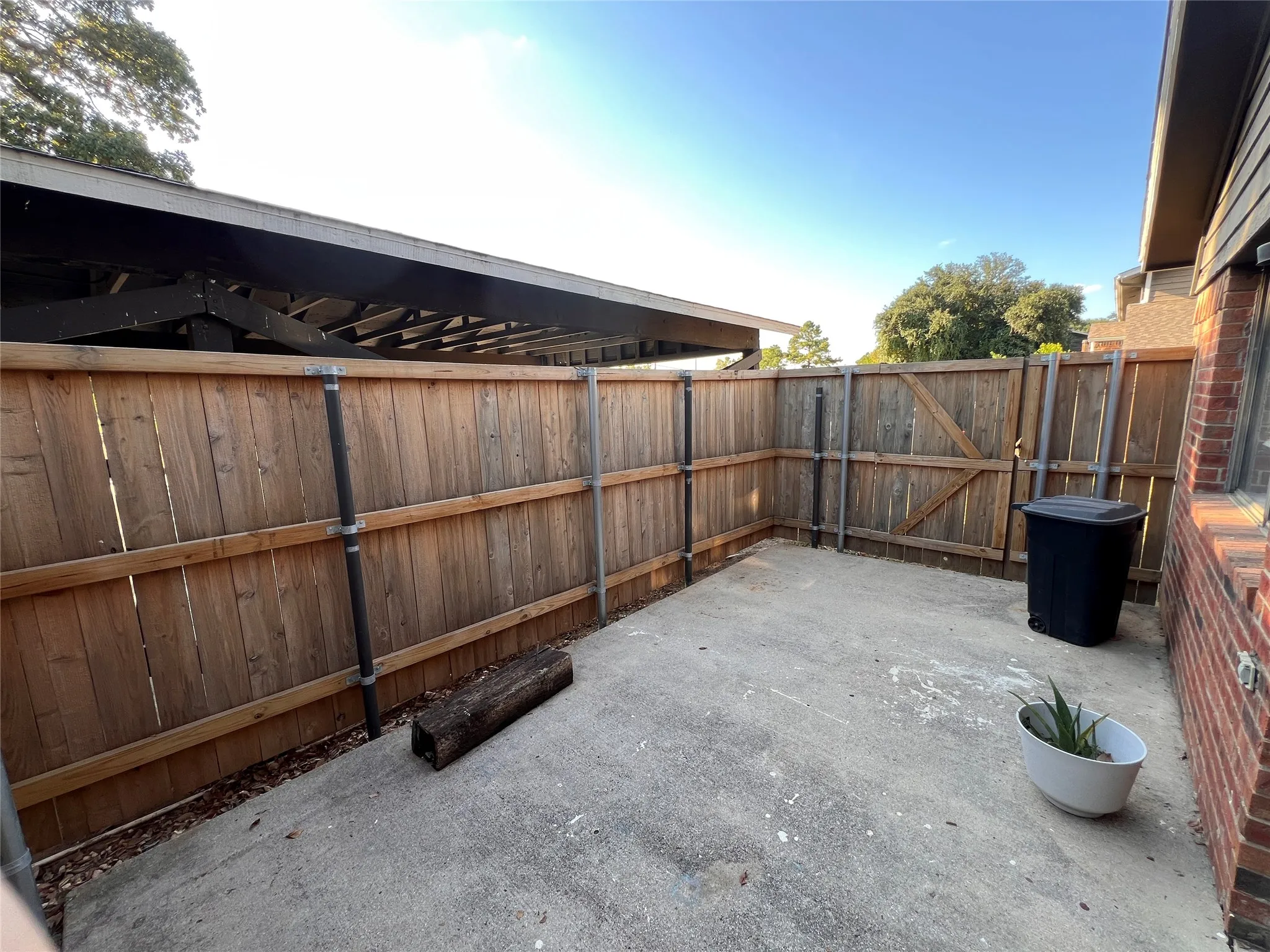 Private concrete patio area with wood fencing and an overhead covered structure