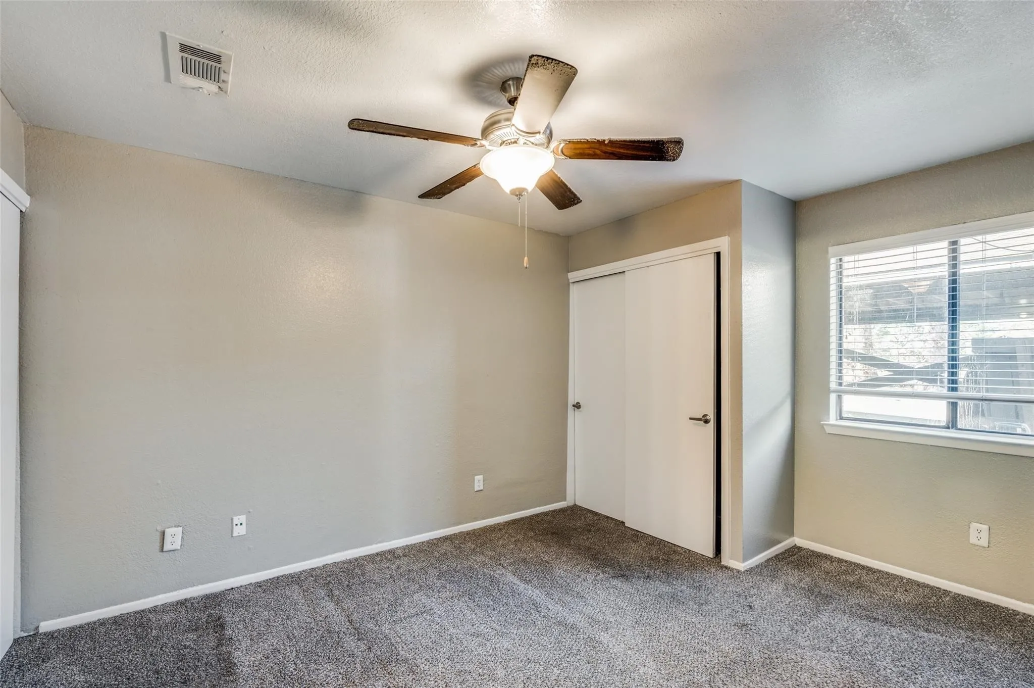 Unfurnished bedroom featuring a closet, dark colored carpet, ceiling fan, and a textured ceiling