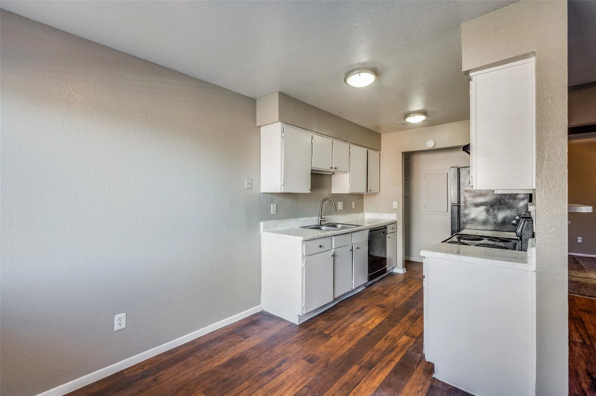 Kitchen featuring light countertops, white cabinets, dark wood-style flooring, and black appliances