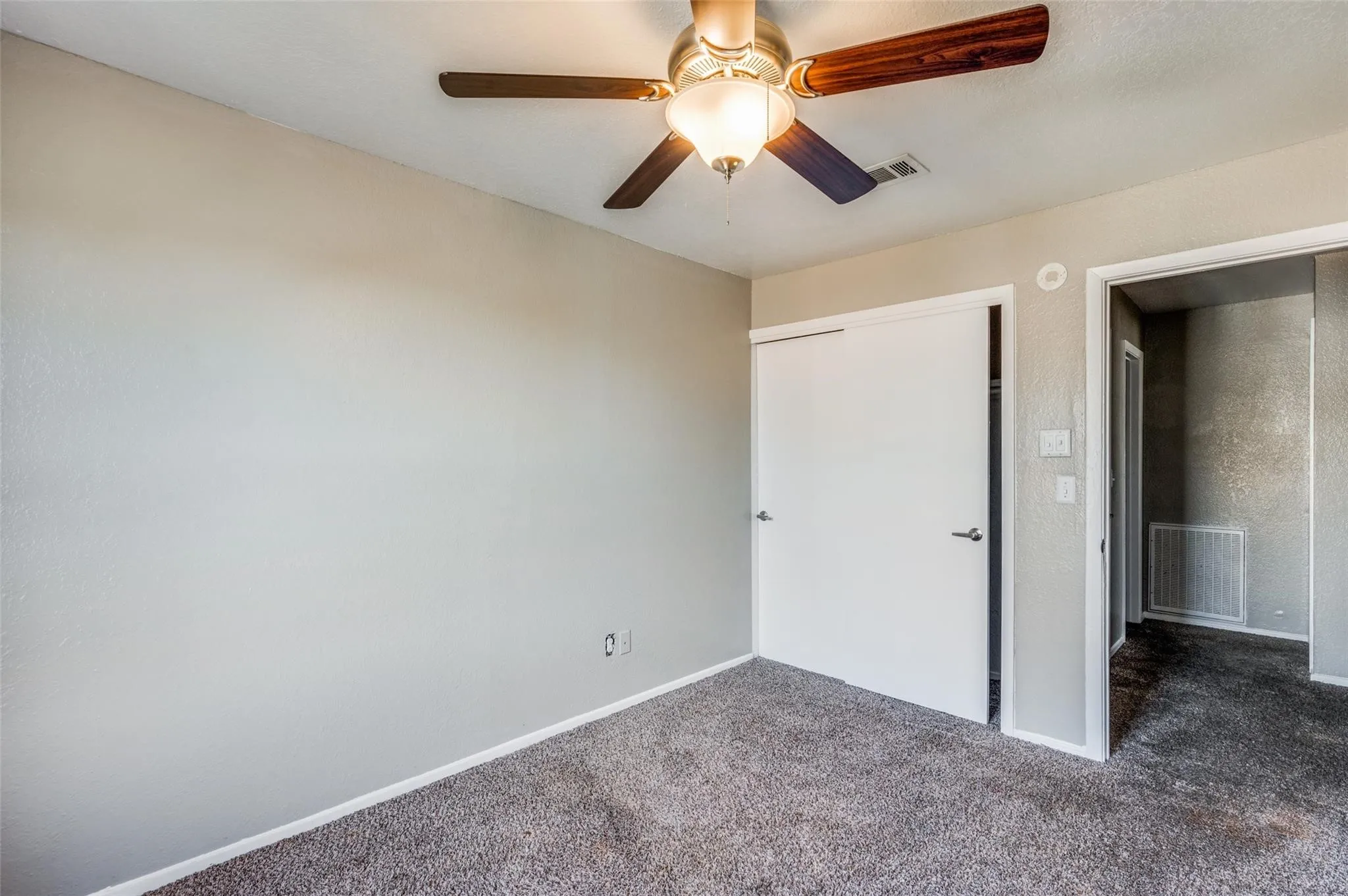 Unfurnished bedroom with dark colored carpet, a closet, and ceiling fan