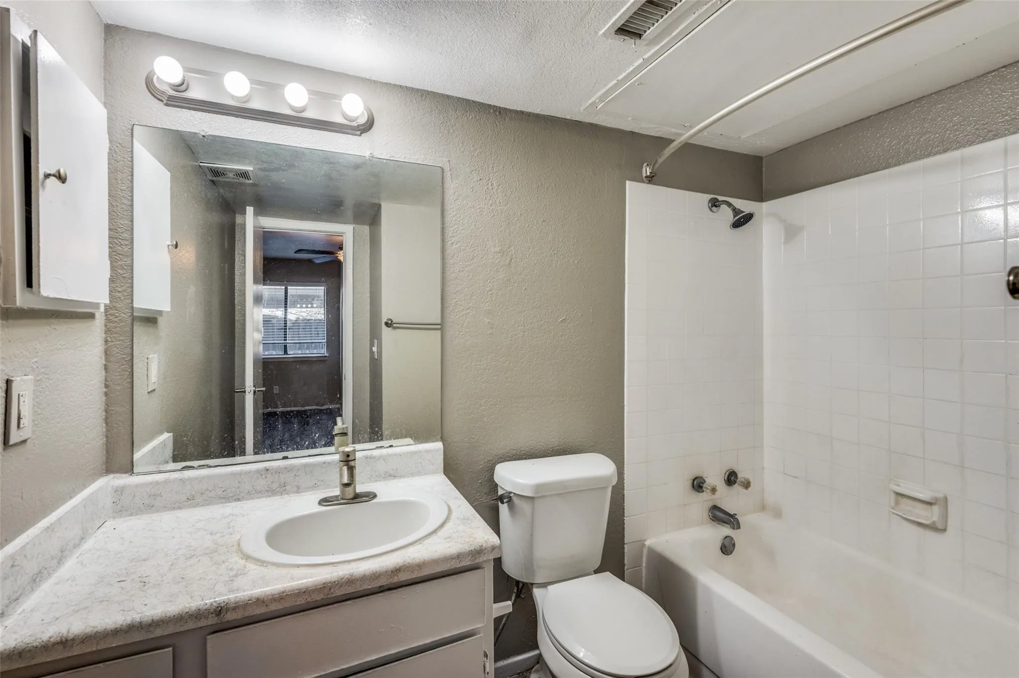 Full bath featuring a textured wall, vanity, shower / bath combination, and a textured ceiling