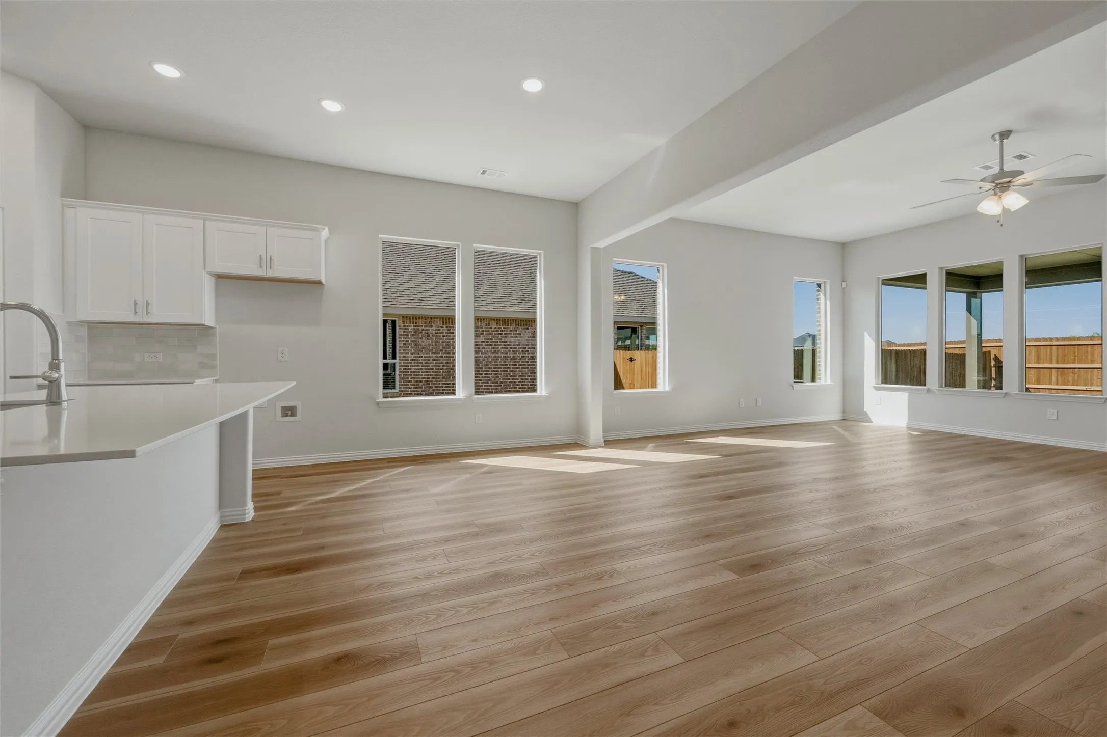 Open-concept living area with wood-finish flooring, recessed lighting, and a ceiling fan