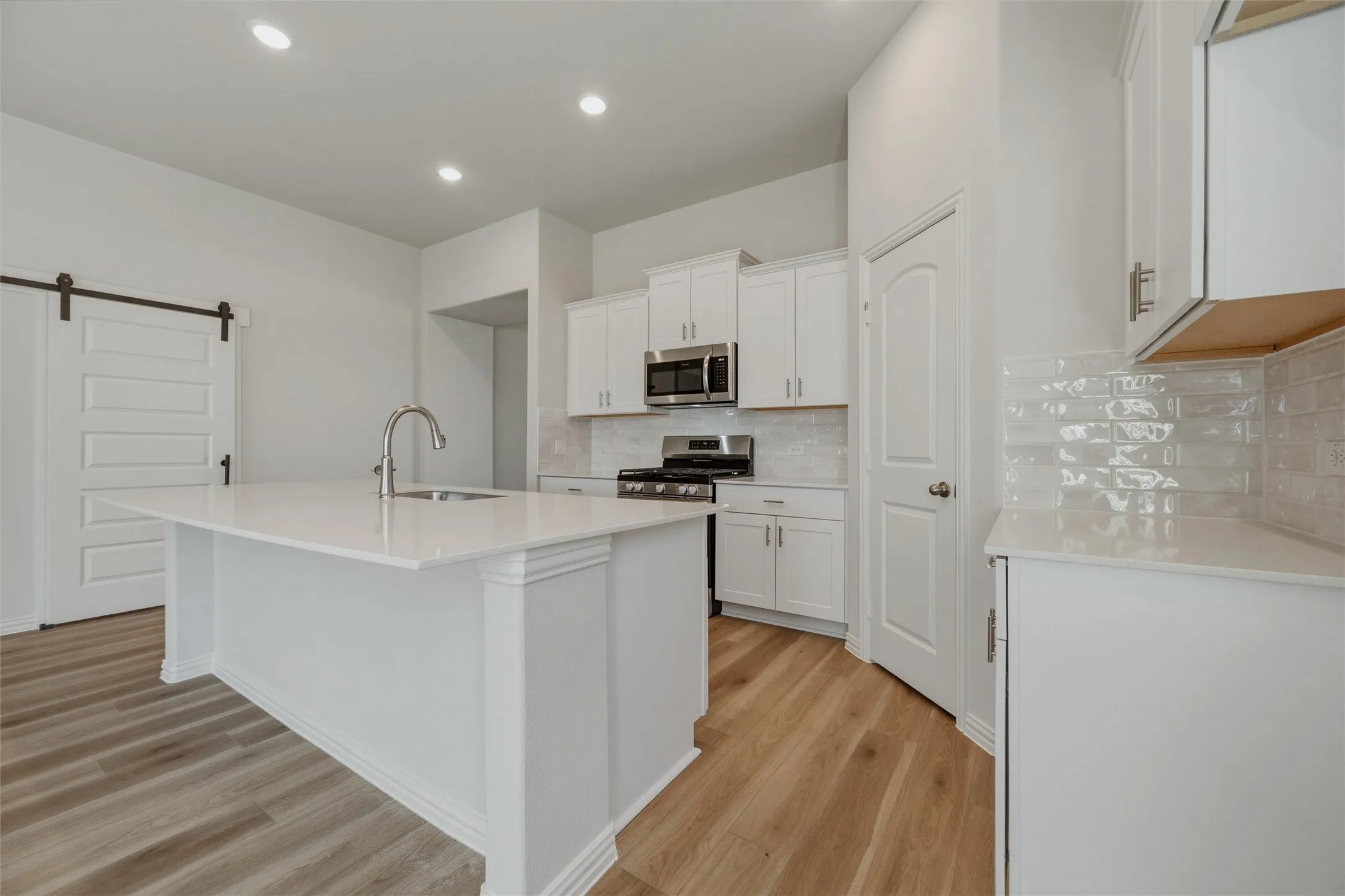 White kitchen island with an undermount sink, stainless steel faucet, and white countertops
