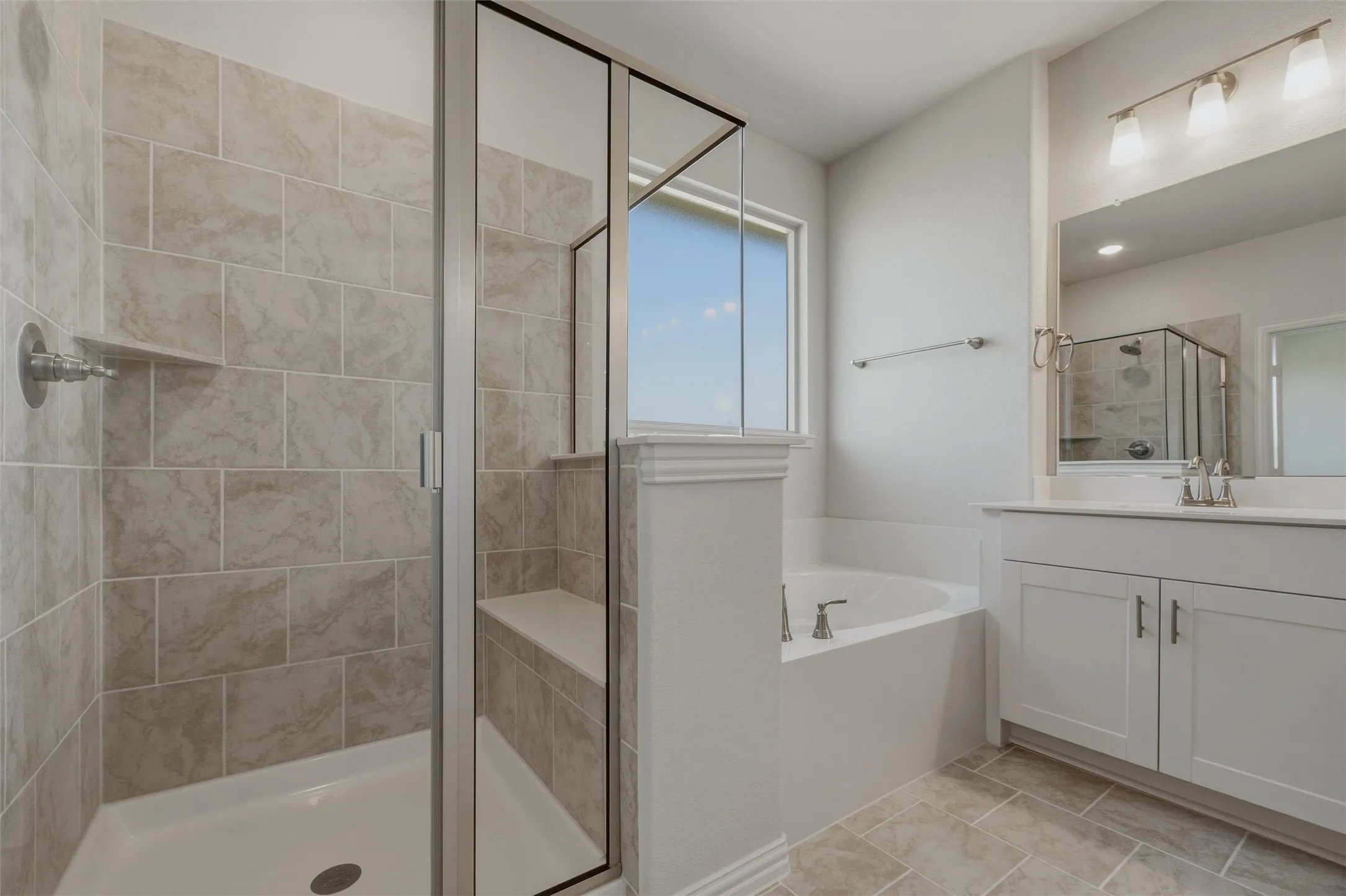 Glass-enclosed shower with a built-in bench, tiled walls, and a recessed shelf