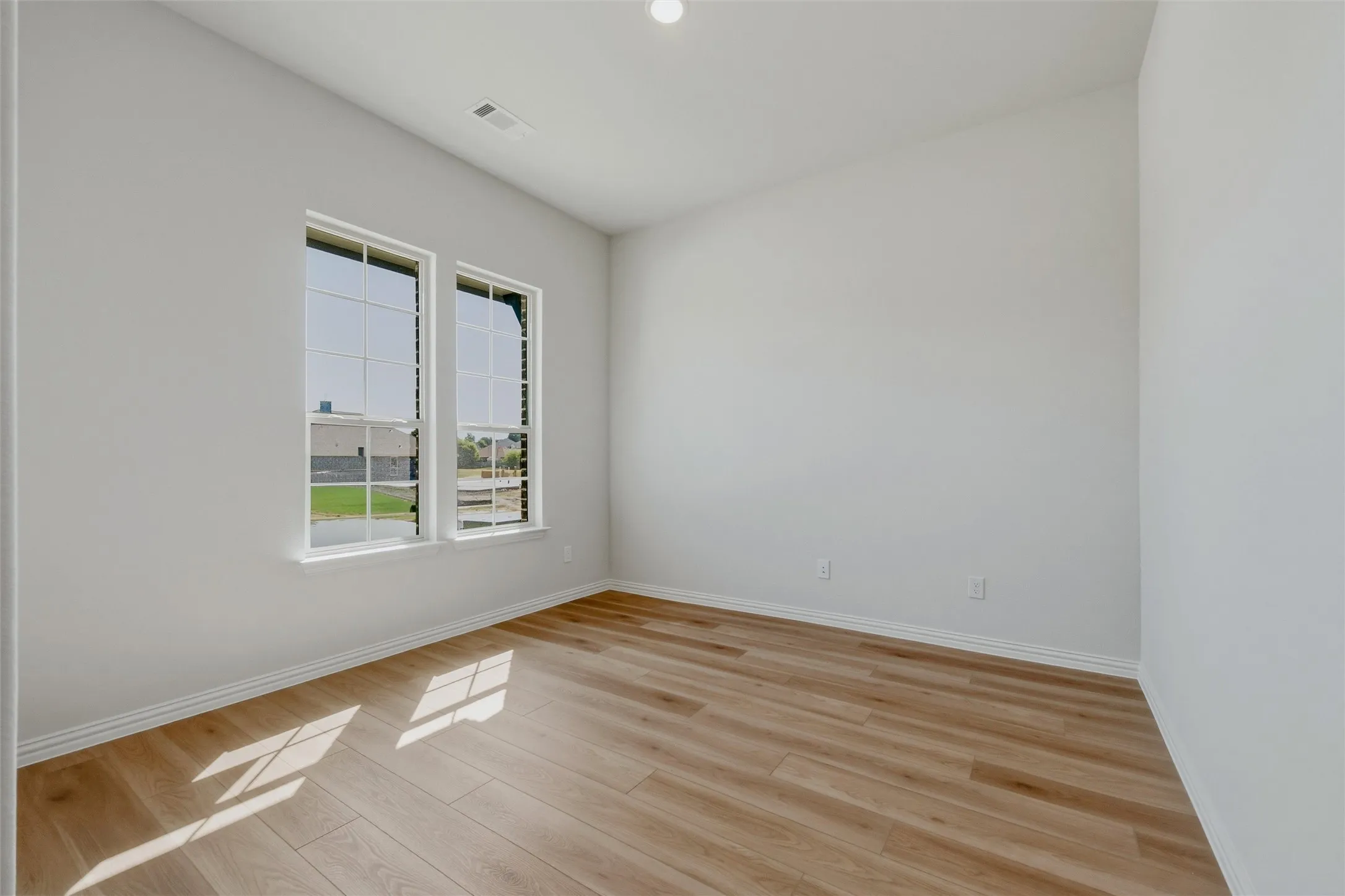 Recessed lighting, wood-finish flooring, white trim, dual windows, and light-toned walls