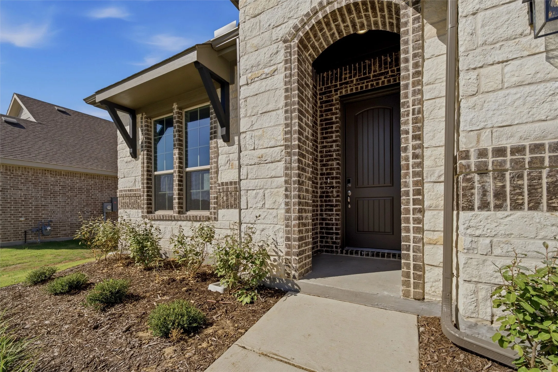 Stone and brick exterior featuring an arched entry and dark wood-finish door