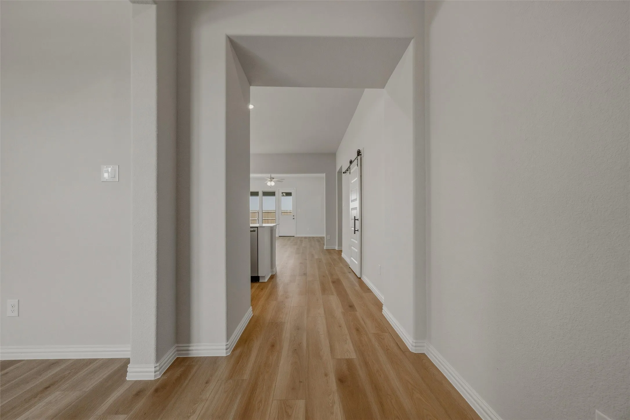 Wood-finish flooring throughout, bright white walls, and a barn door with black hardware