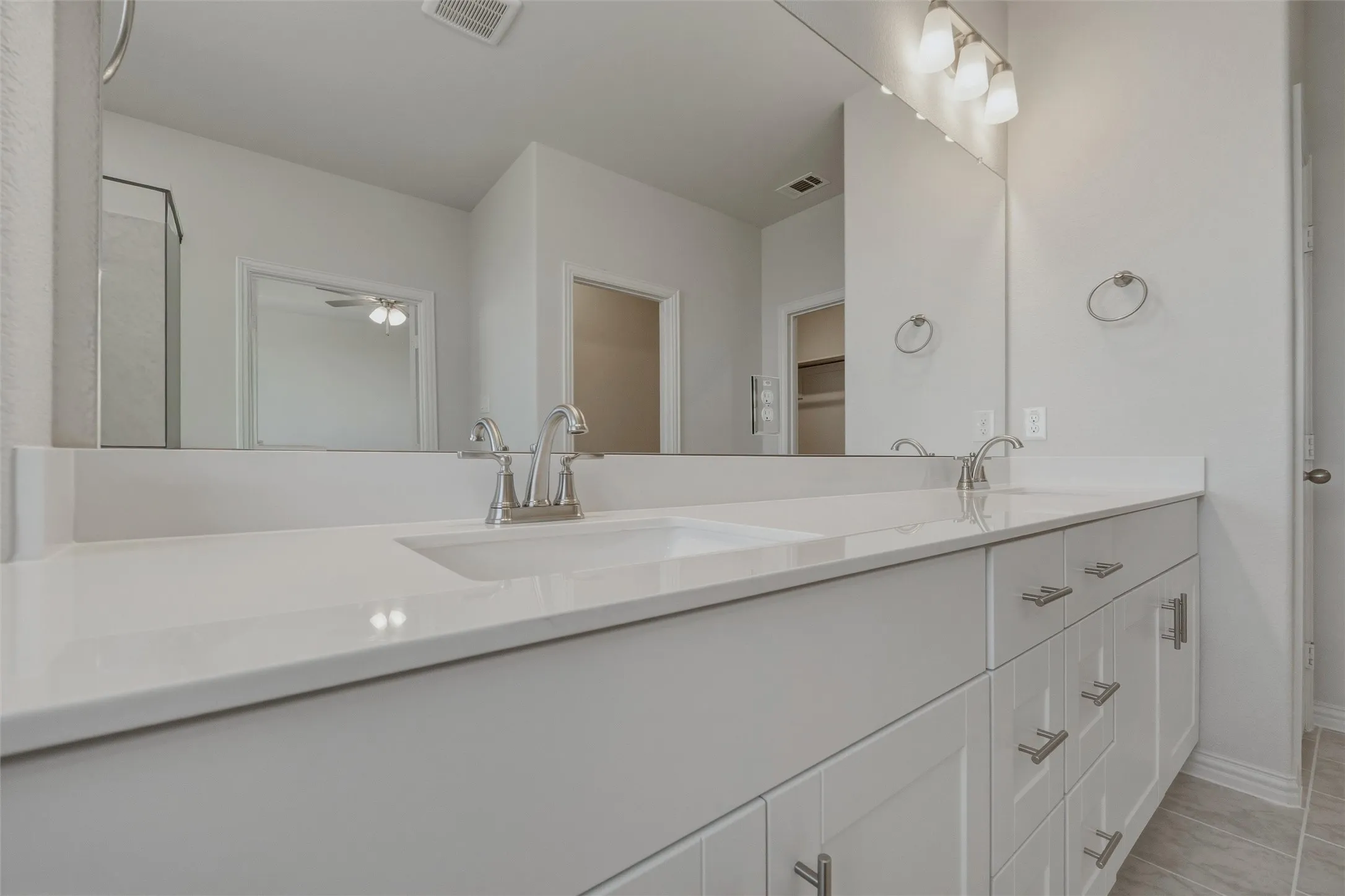 Dual vanity with integrated sinks, white cabinetry, and brushed nickel fixtures