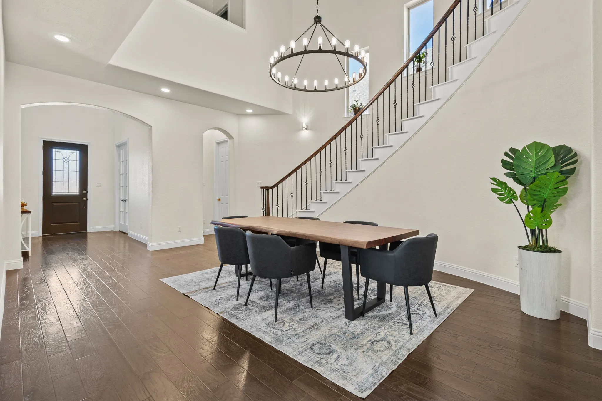 Dining space with arched walkways, dark wood-type flooring, stairs, baseboards, and recessed lighting
