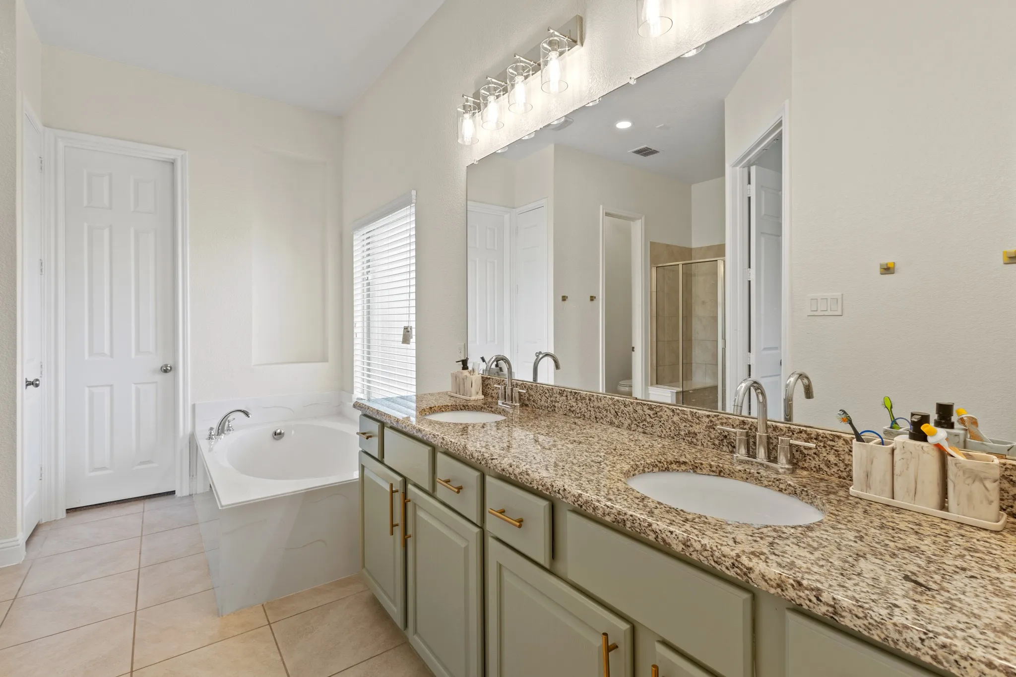 Bathroom featuring a stall shower, a garden tub, tile patterned flooring, and double vanity