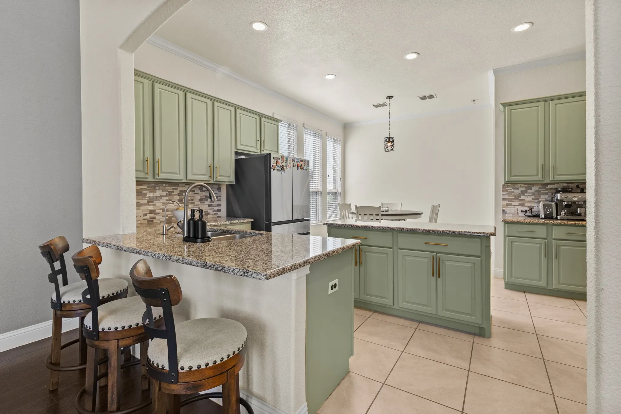 Kitchen featuring green cabinets, a sink, freestanding refrigerator, ornamental molding, and arched walkways