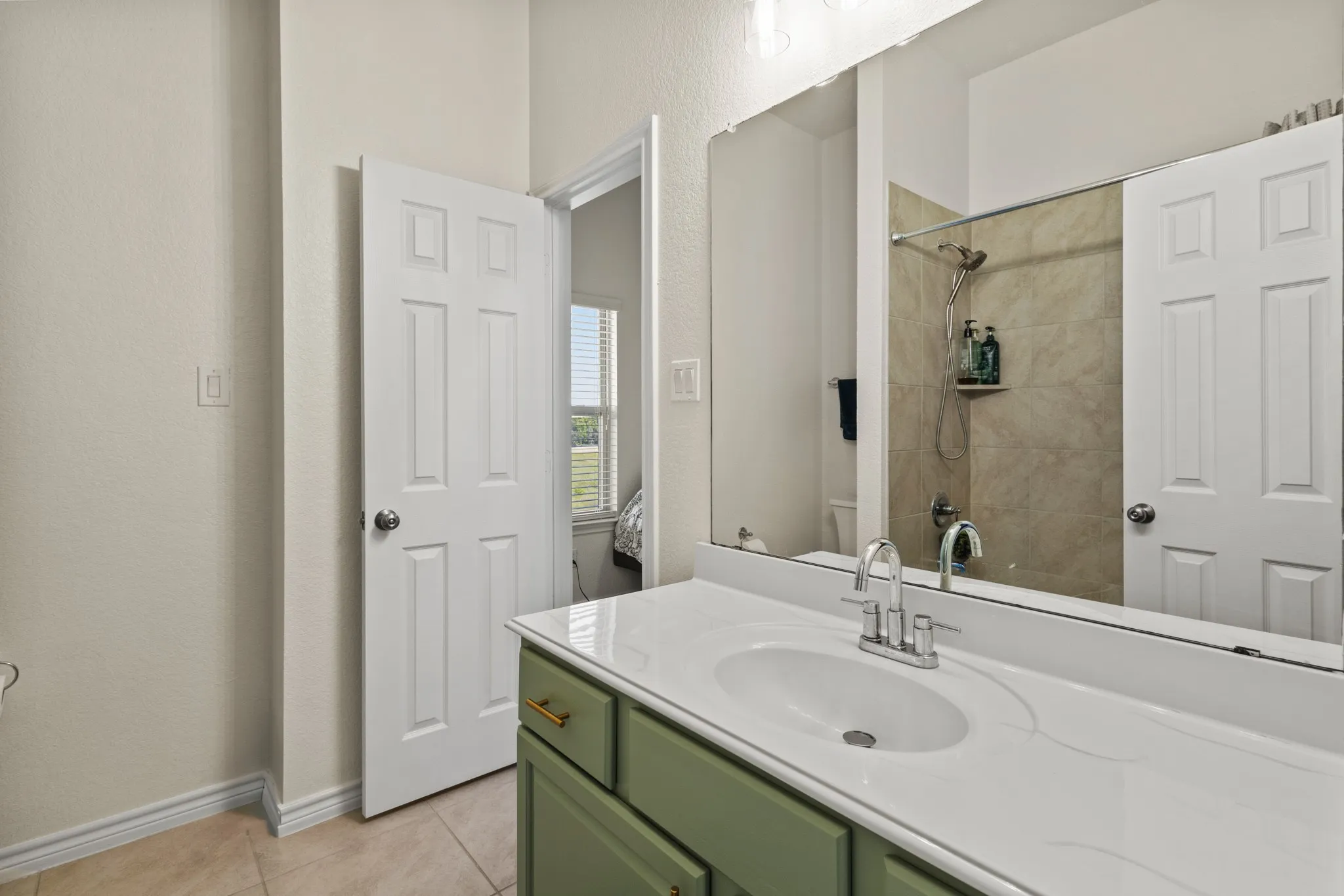 Full bath with toilet, tile patterned floors, vanity, baseboards, and a tile shower