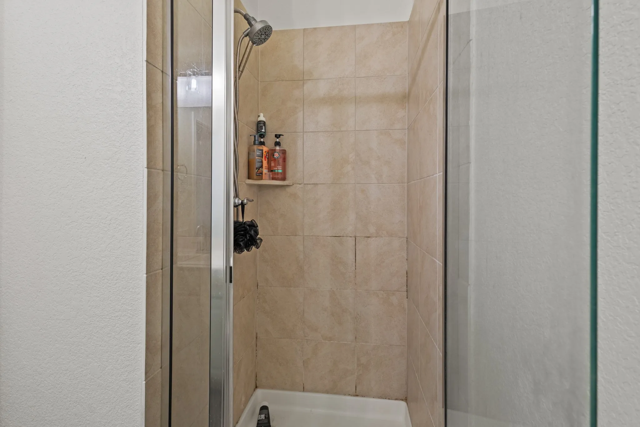 Bathroom with a shower stall and a textured wall