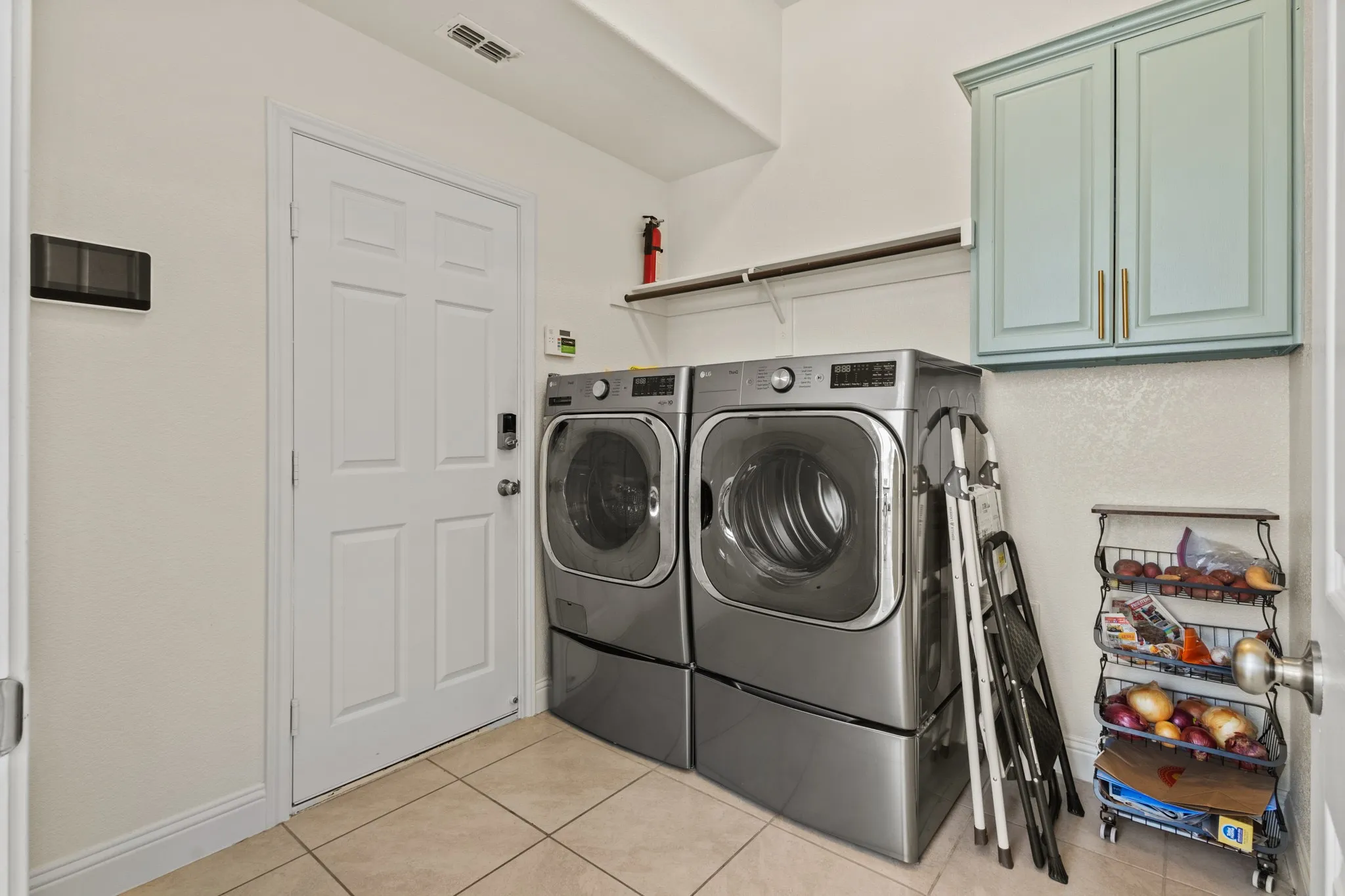 Laundry room featuring cabinet space, washer and dryer, light tile patterned floors, and baseboards