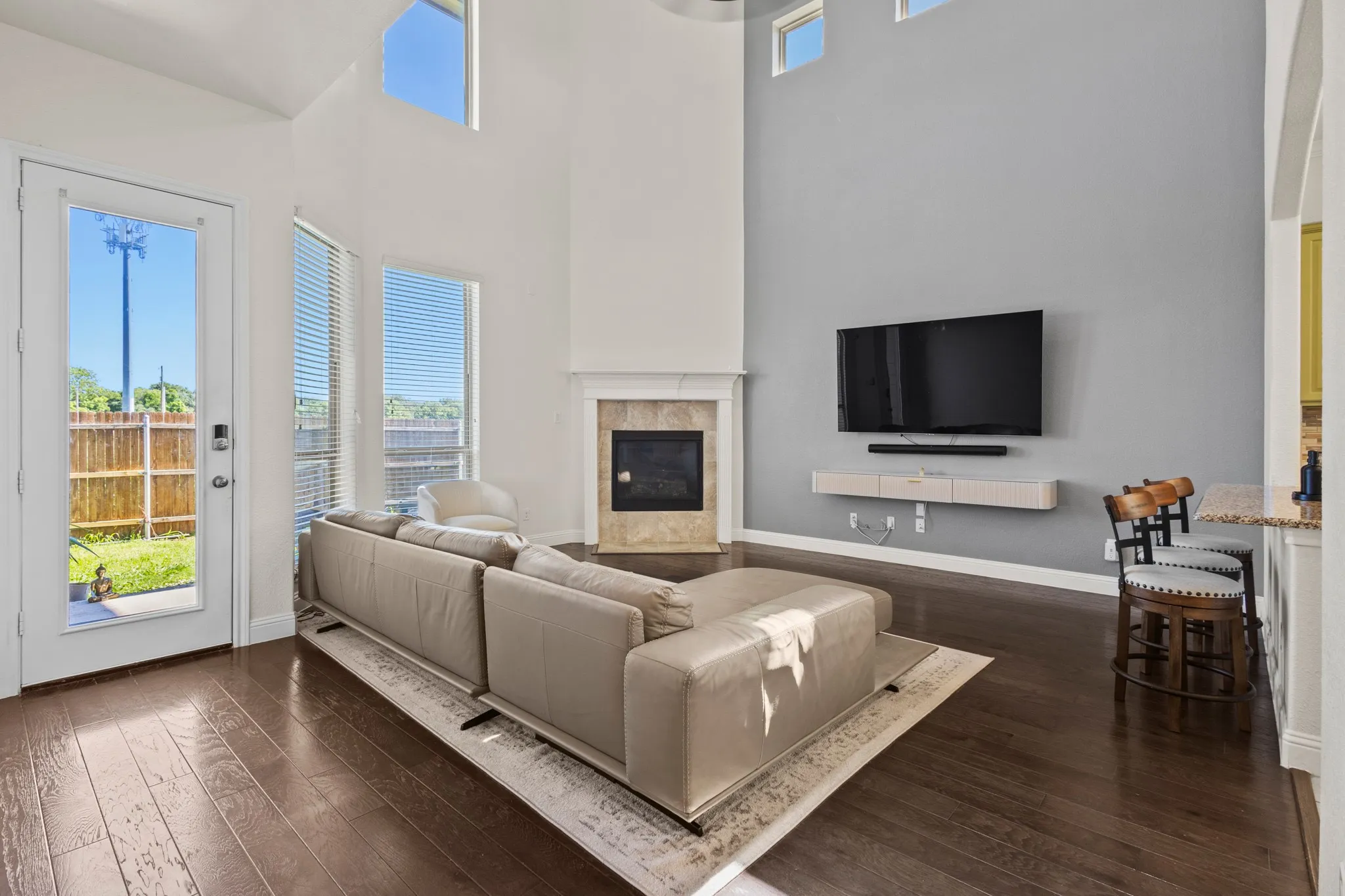 Living room with a fireplace, a high ceiling, dark wood-style floors, and baseboards