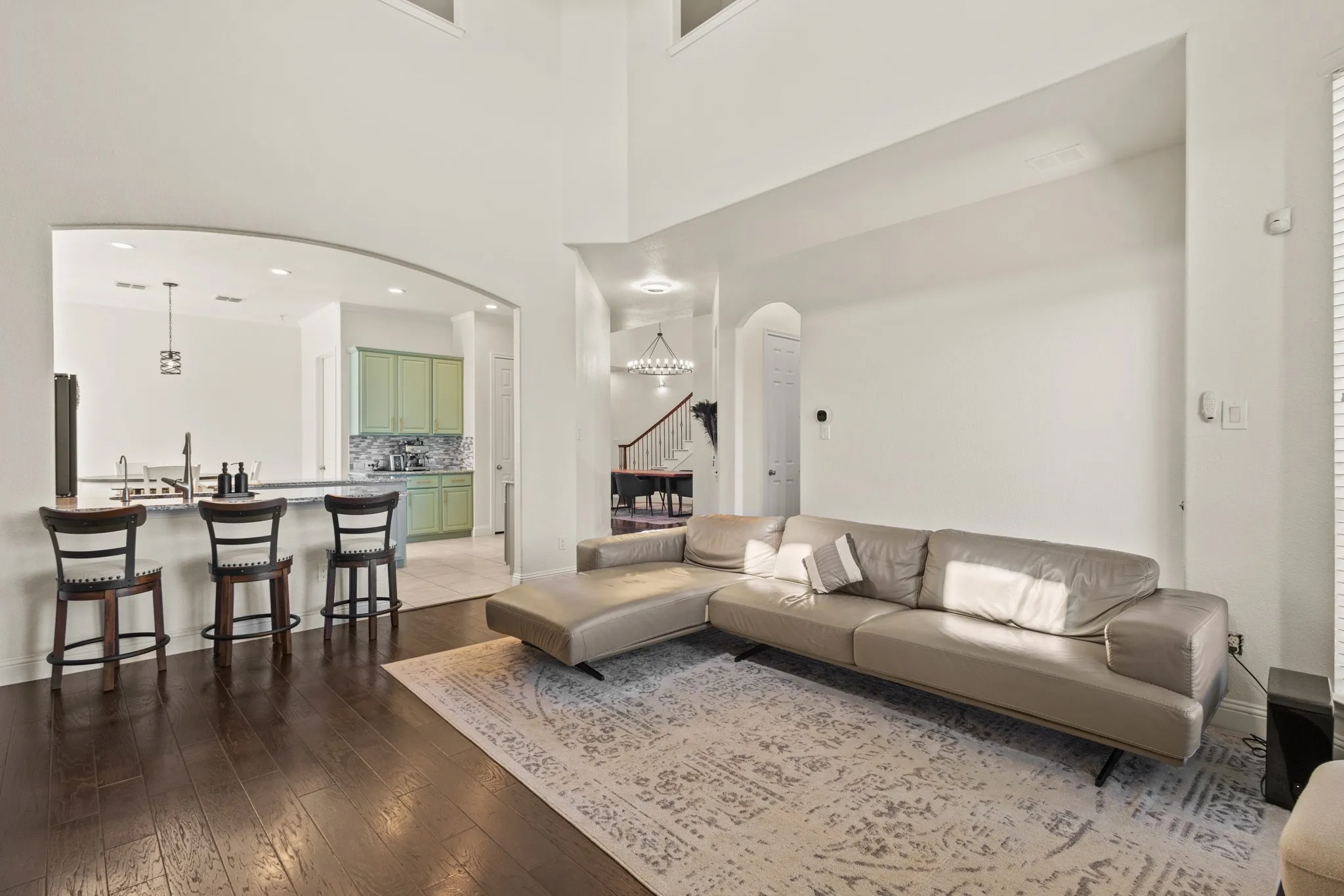 Living area with arched walkways, stairway, hardwood / wood-style floors, baseboards, and a towering ceiling