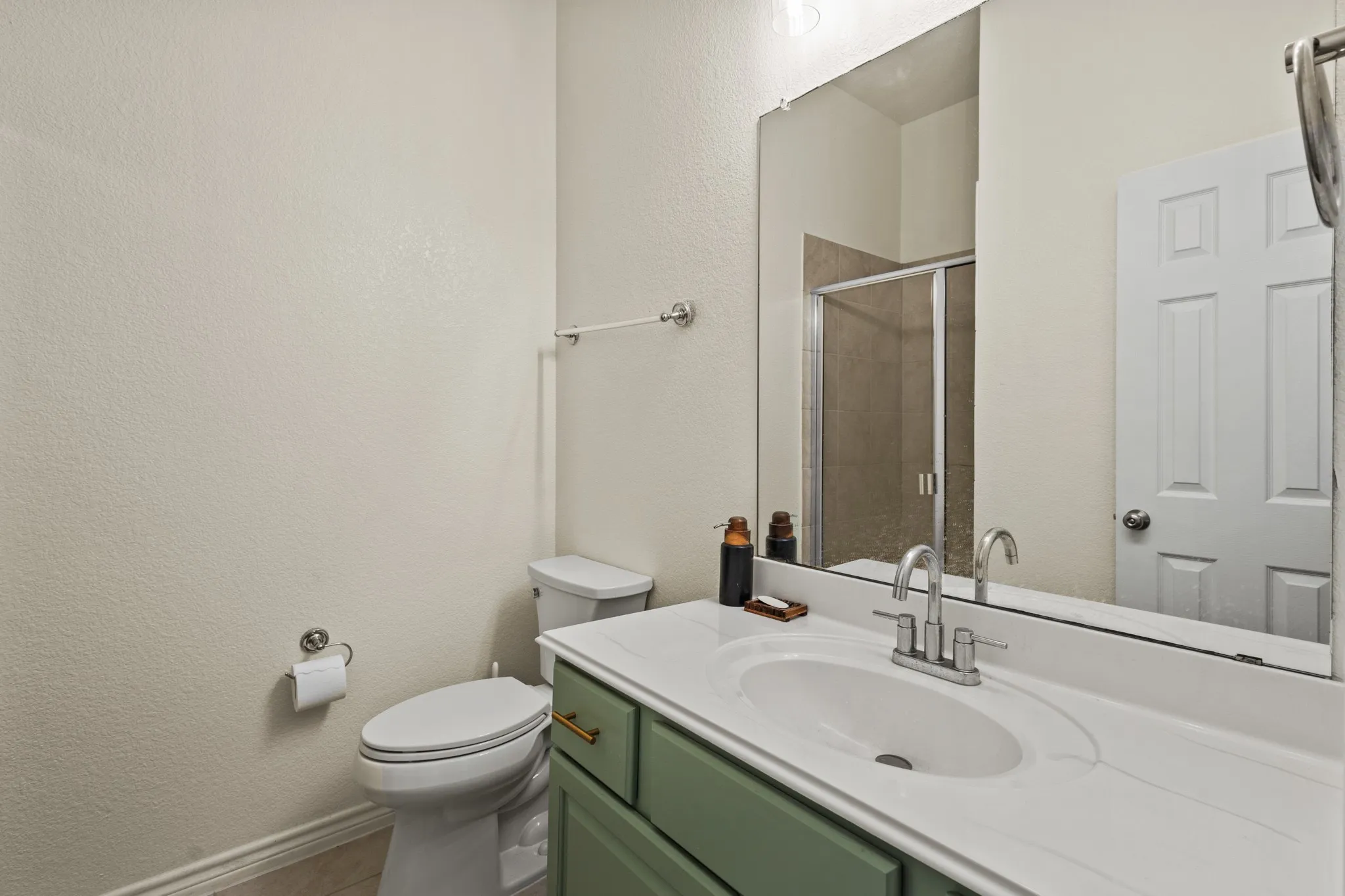 Bathroom with a shower stall, toilet, vanity, baseboards, and a textured wall