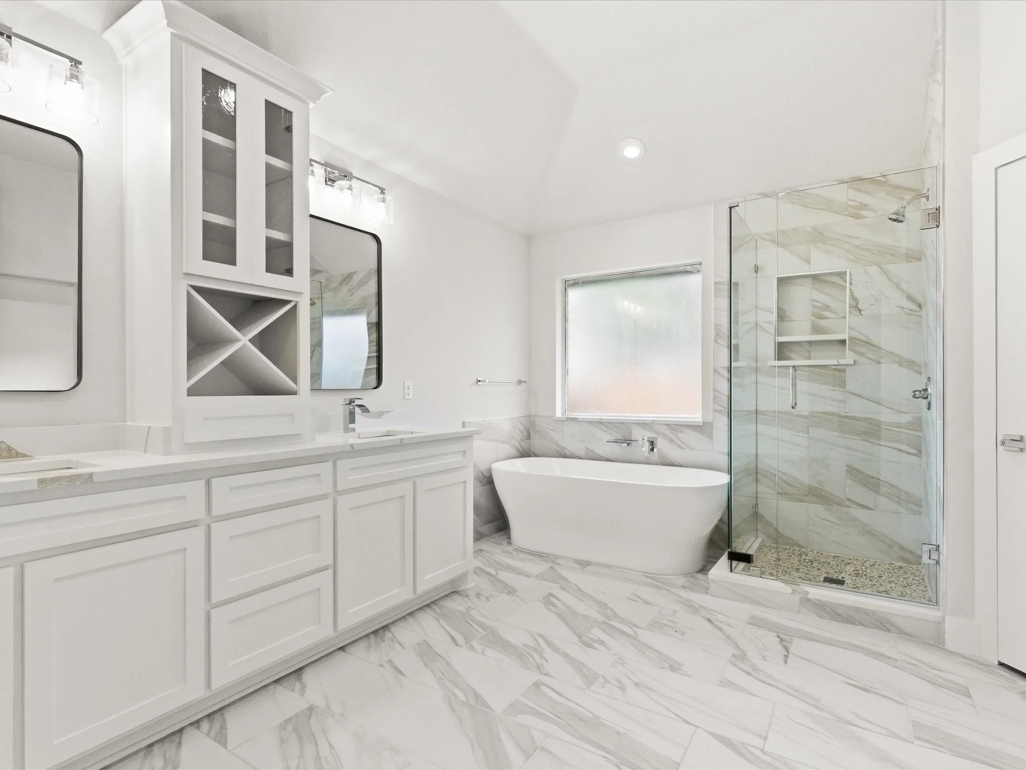 Bathroom with wainscoting, double vanity, a marble finish shower, tile walls, and a freestanding tub