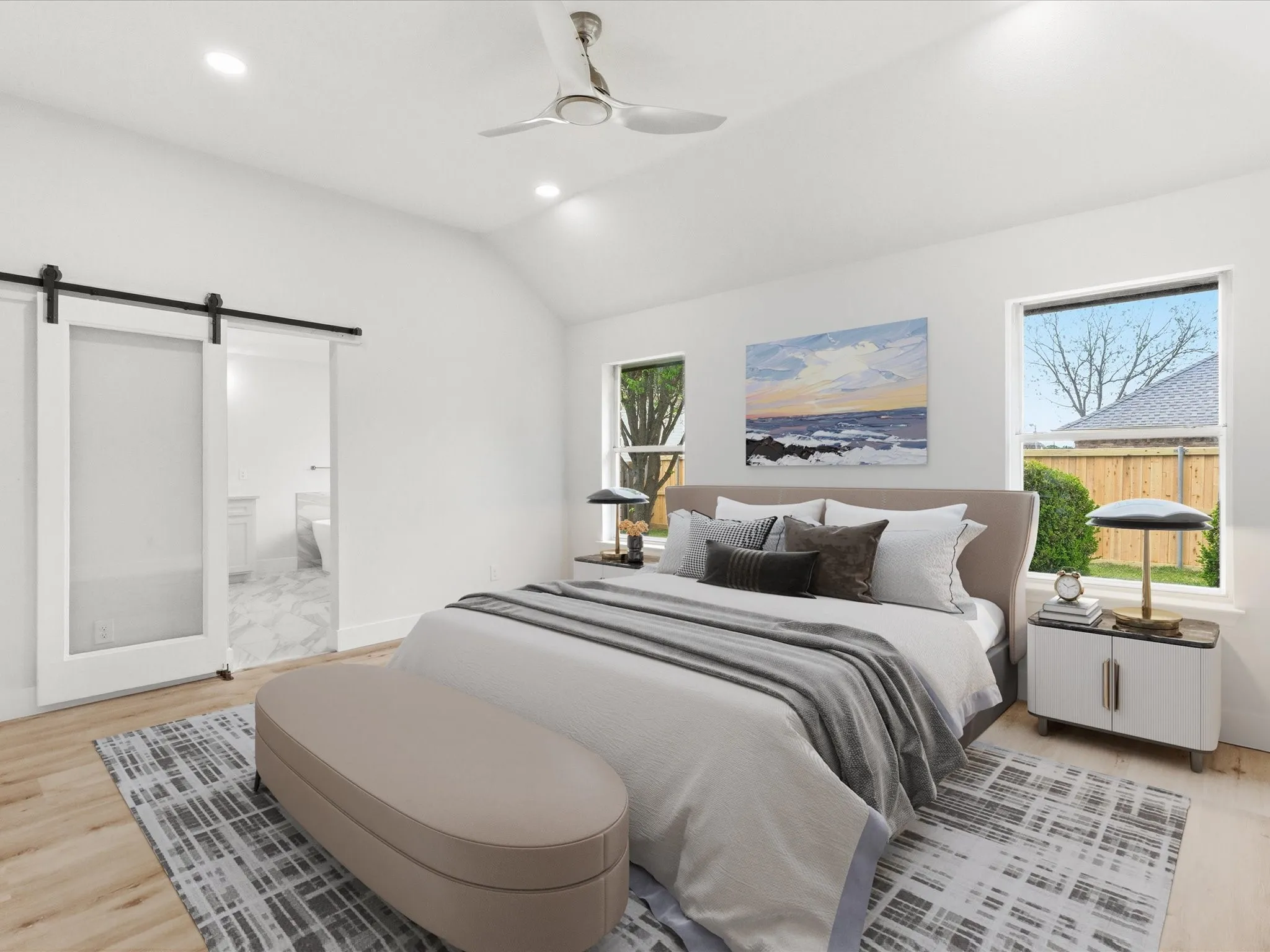 Bedroom with a barn door, light wood-style floors, vaulted ceiling, ceiling fan, and connected bathroom