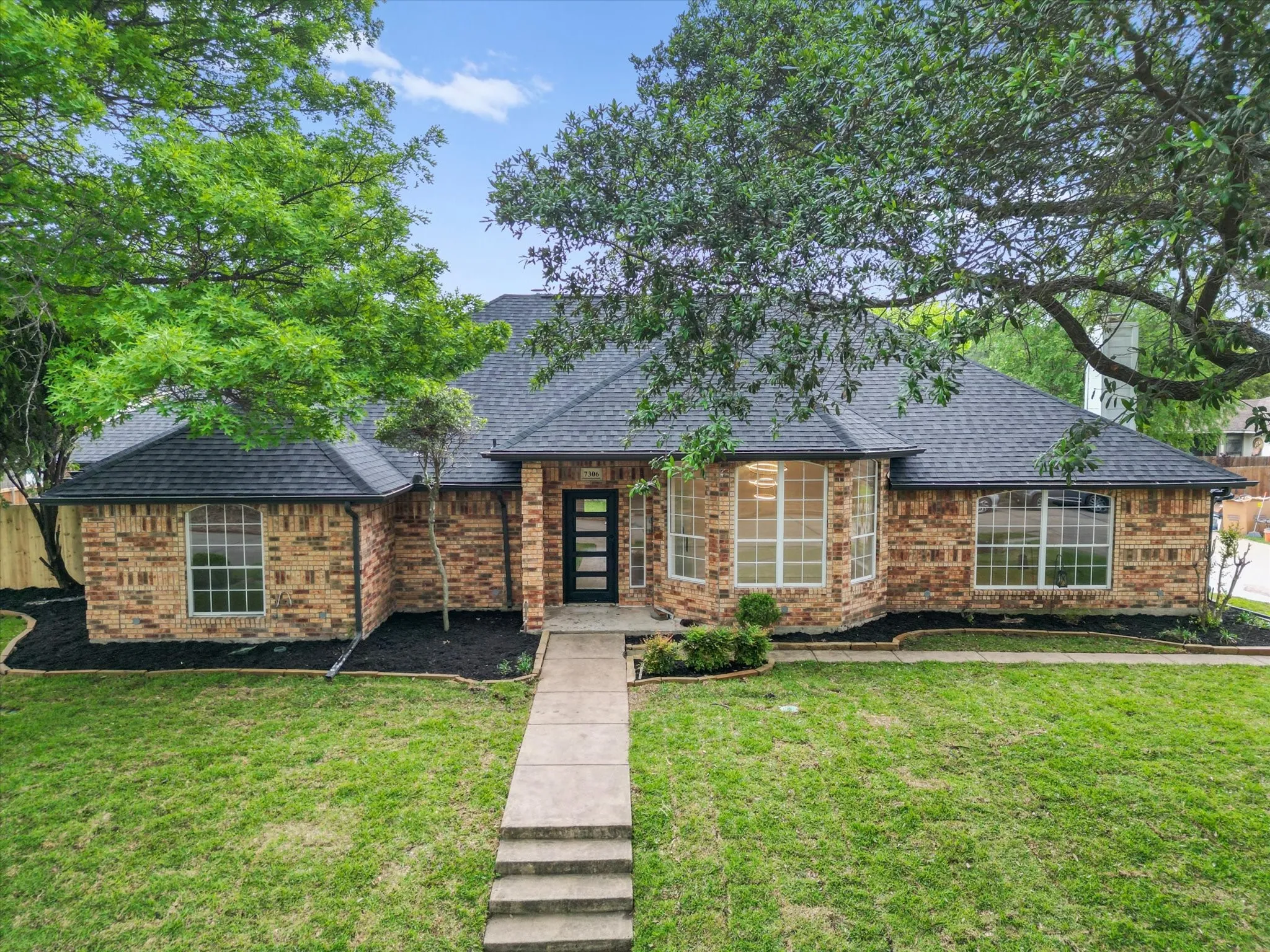 View of front of property featuring brick siding, a shingled roof, and a front yard