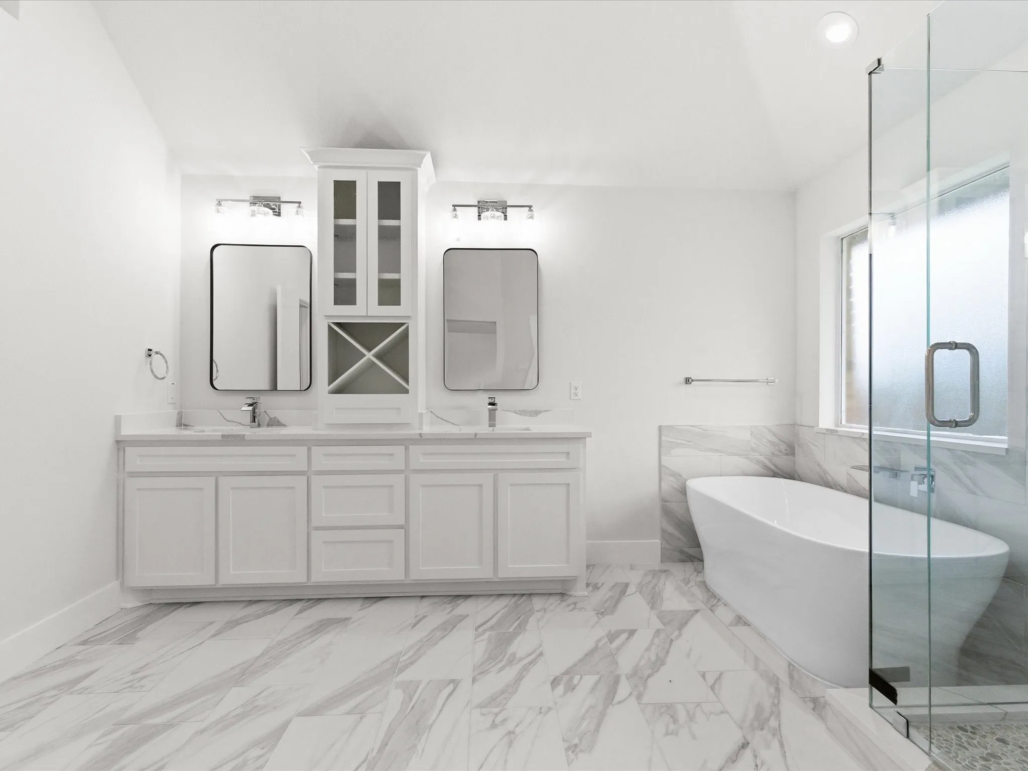 Full bath with double vanity, a freestanding tub, a marble finish shower, light marble finish floors, and vaulted ceiling