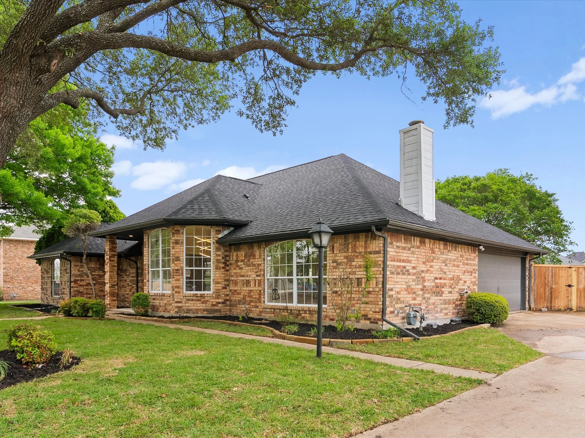 Ranch-style home featuring brick siding, a shingled roof, a chimney, and a front lawn