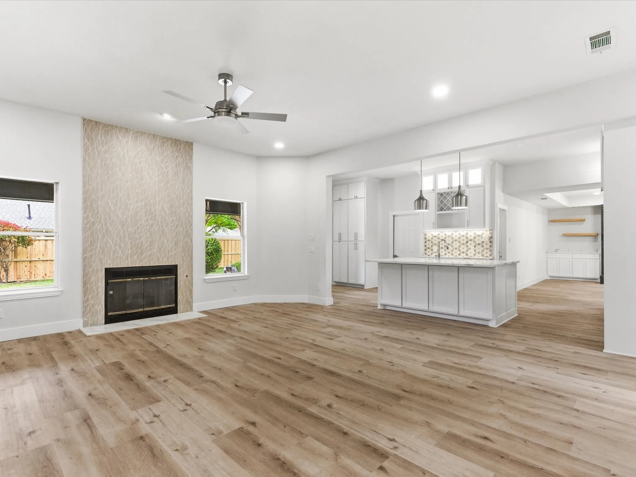 Unfurnished living room featuring a ceiling fan, a fireplace, light wood-style floors, and recessed lighting