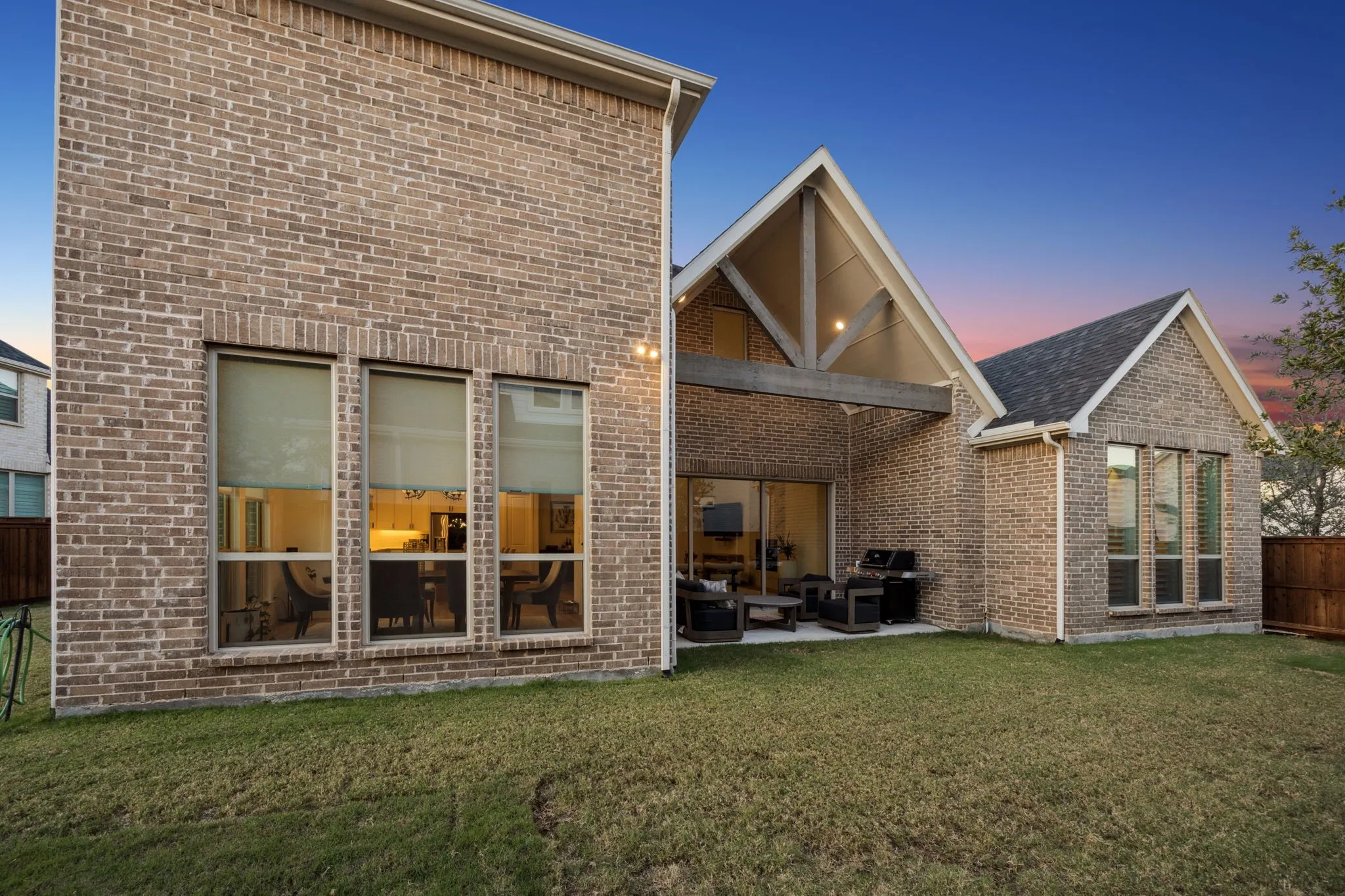 Back house at dusk with a lawn and a patio area