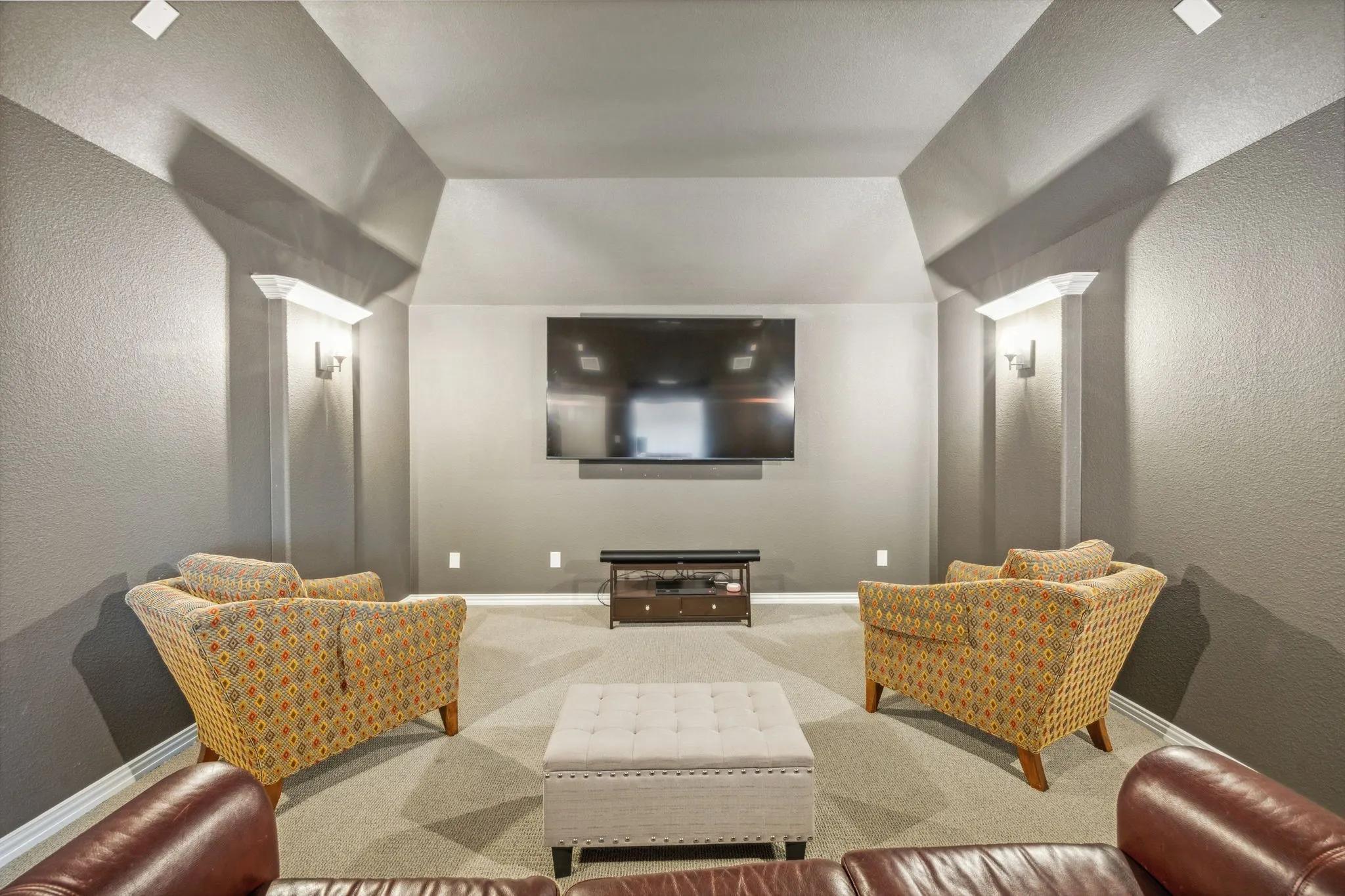 Carpeted cinema room featuring decorative columns and lofted ceiling