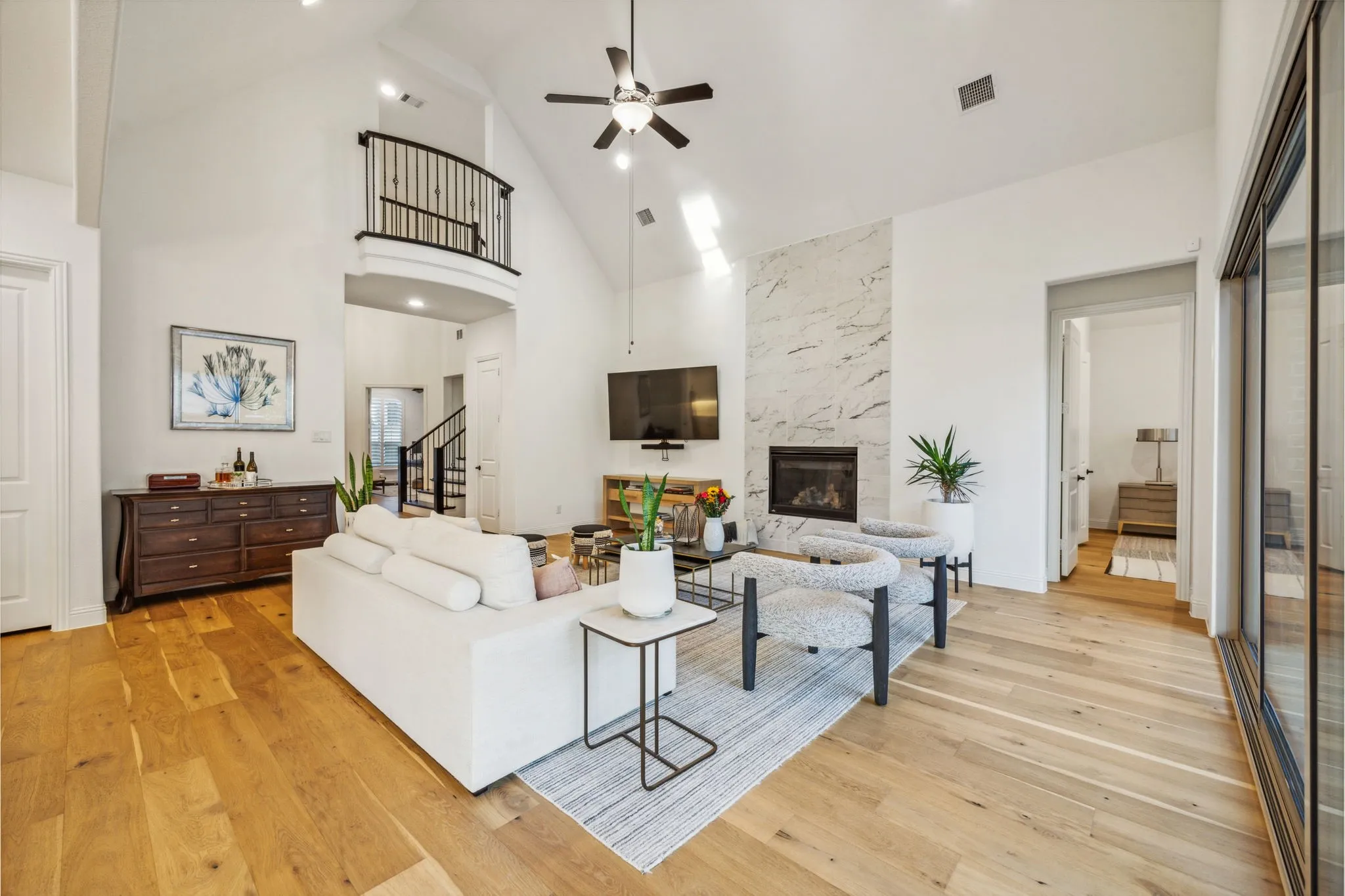 Living room with ceiling fan, a fireplace, high vaulted ceiling, and light hardwood / wood-style flooring