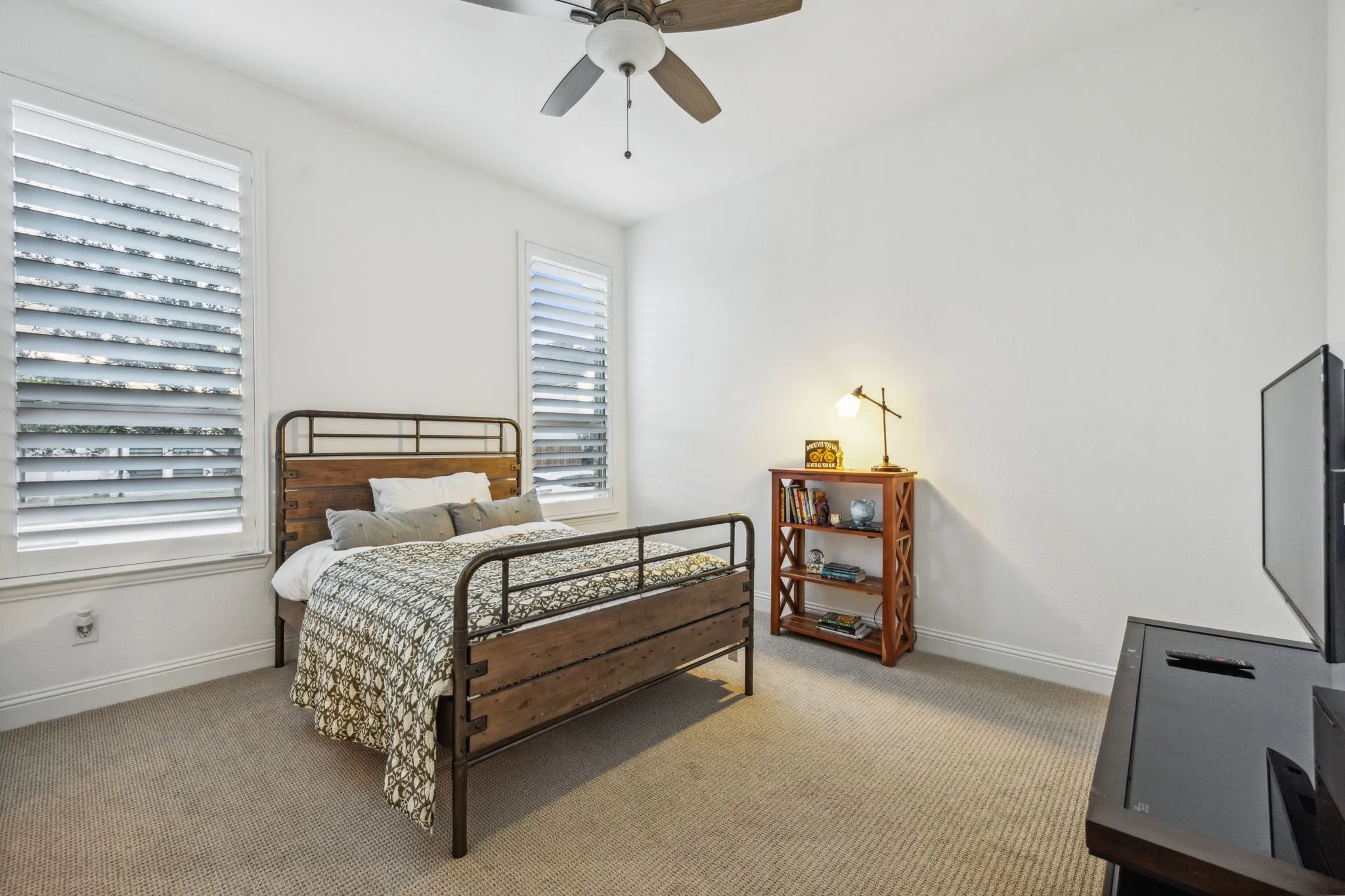 Carpeted bedroom with ceiling fan and multiple windows