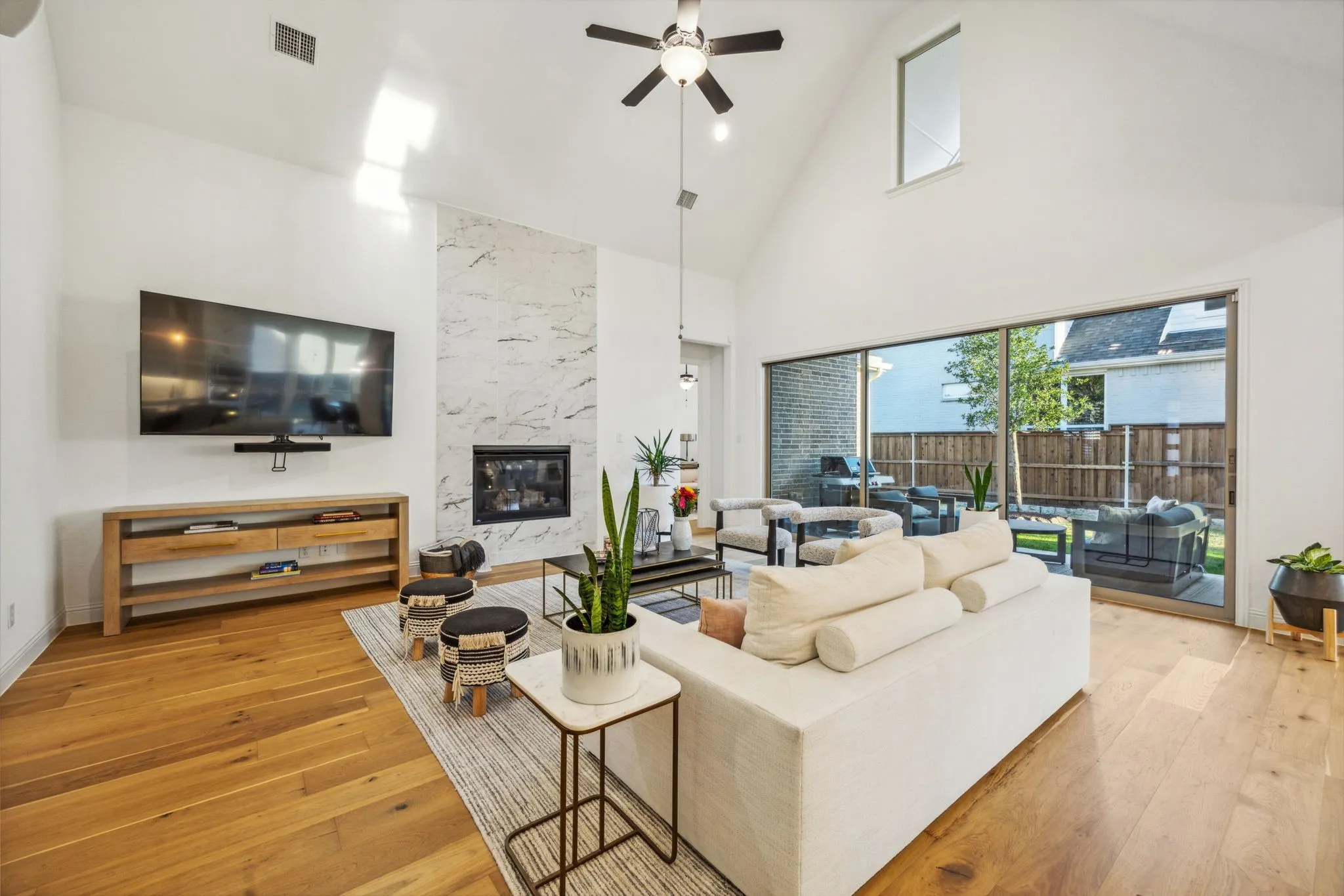 Living room with a high end fireplace, high vaulted ceiling, light hardwood / wood-style floors, and ceiling fan