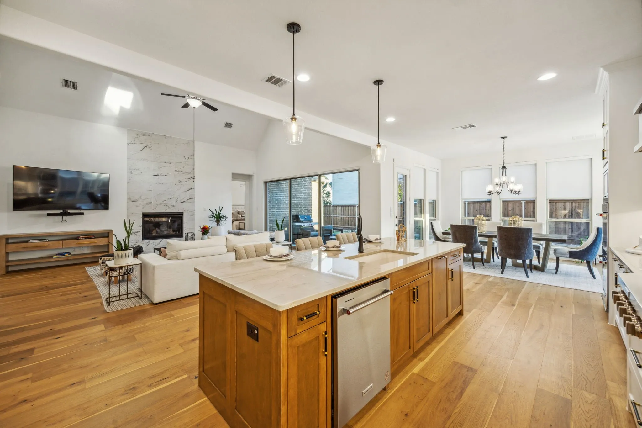 Kitchen with dishwasher, sink, hanging light fixtures, an island with sink, and ceiling fan with notable chandelier