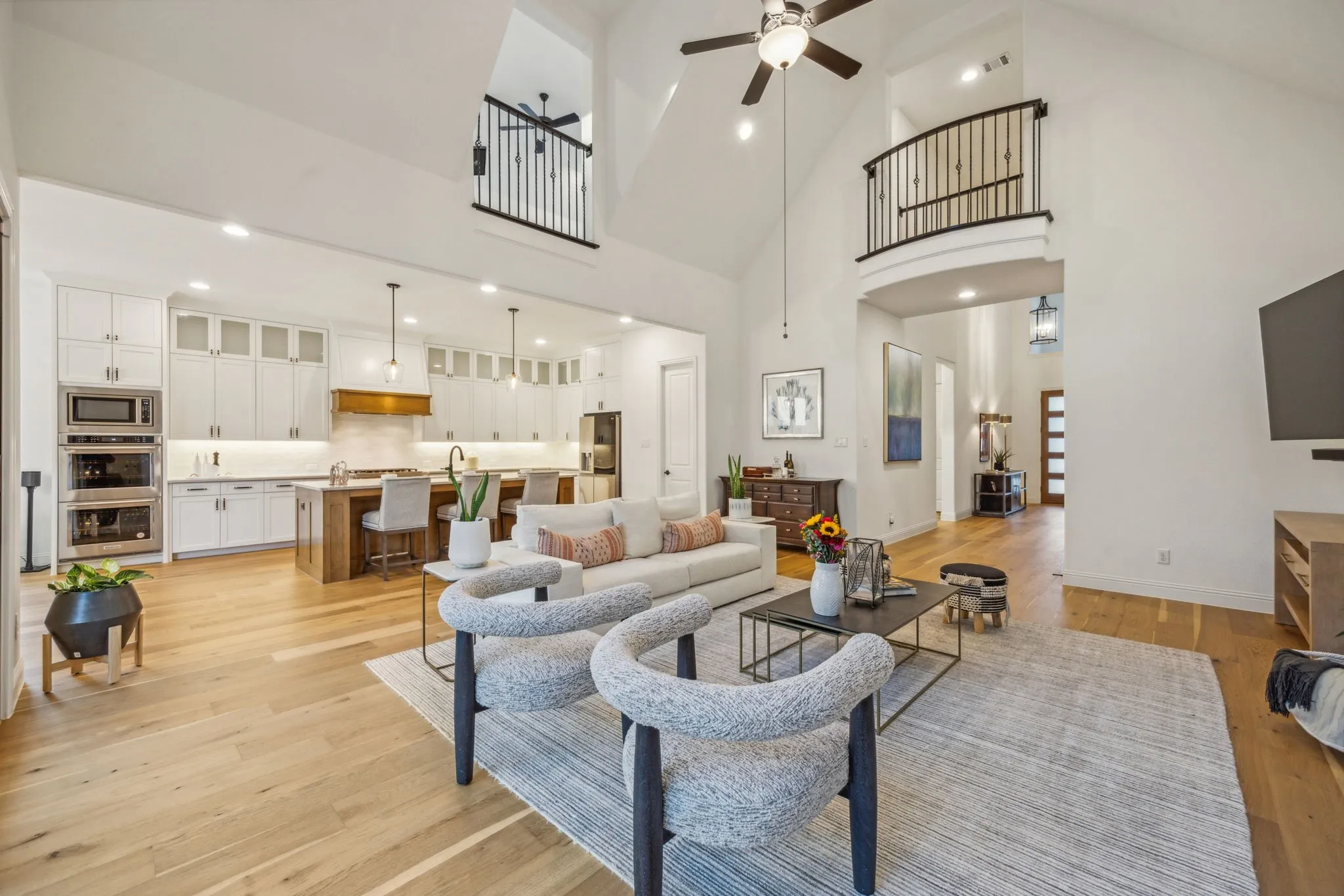 Living room with a towering ceiling, light hardwood / wood-style flooring, ceiling fan, and sink