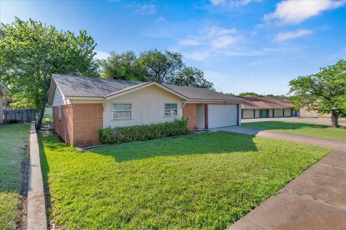 View of front of home featuring brick siding, driveway, a garage, and roof with shingles