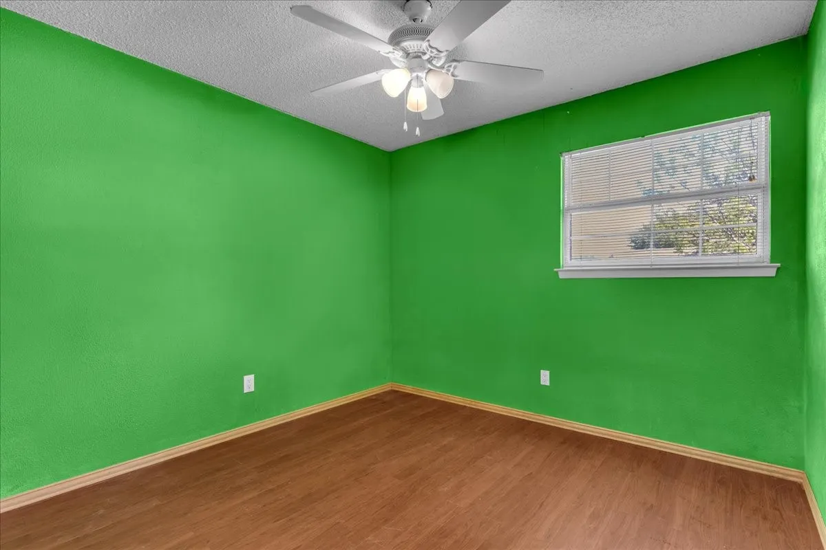 Unfurnished room featuring ceiling fan, dark wood-style flooring, and a textured ceiling