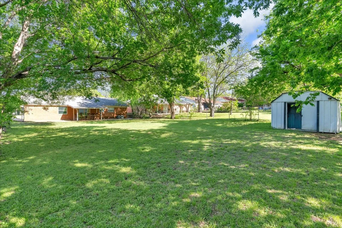 Fenced backyard featuring a shed
