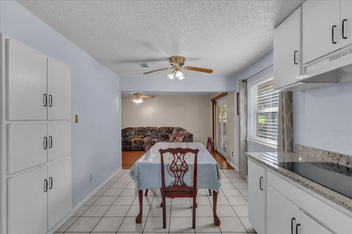 Dining area featuring a textured ceiling, light tile patterned floors, and a ceiling fan