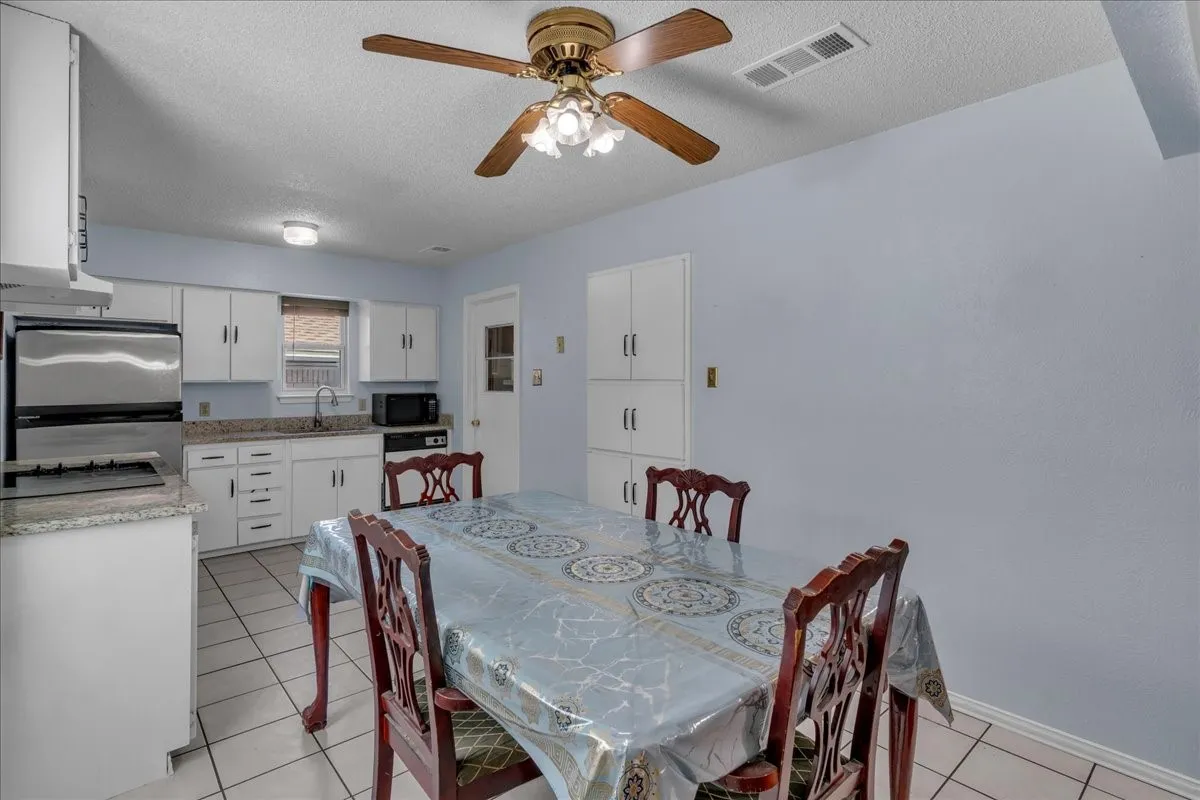 Dining room with a textured ceiling, light tile patterned floors, and a ceiling fan