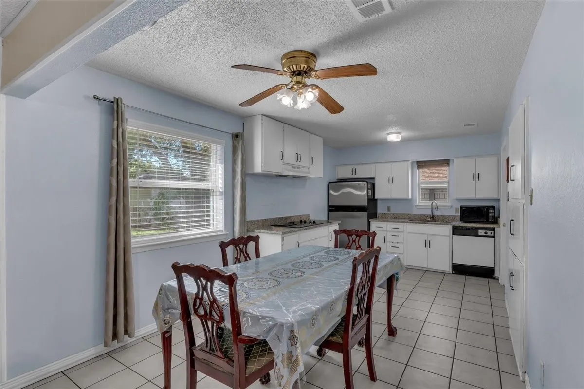 Dining room with a ceiling fan, a textured ceiling, and light tile patterned floors
