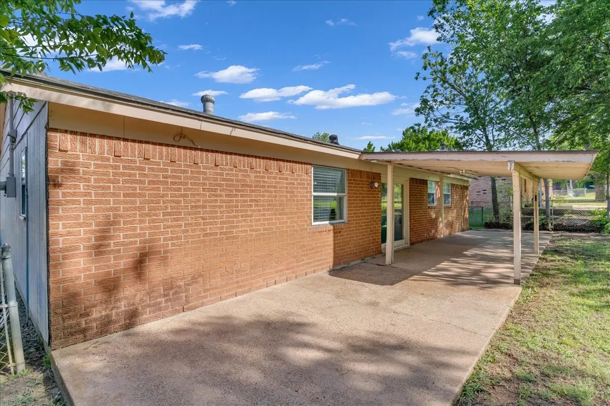 View of side of home featuring an attached carport, a patio, and brick siding