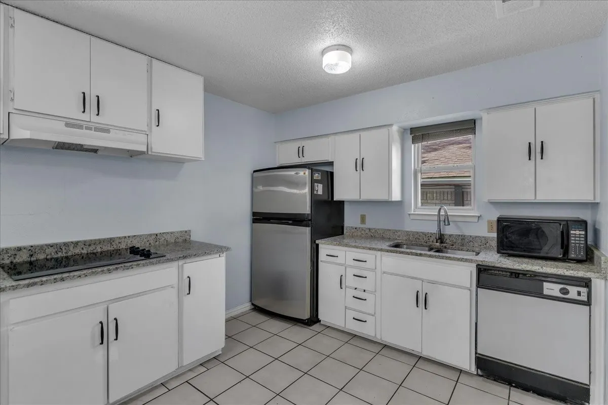 Kitchen featuring white cabinetry, a textured ceiling, black appliances, light stone countertops, and light tile patterned floors