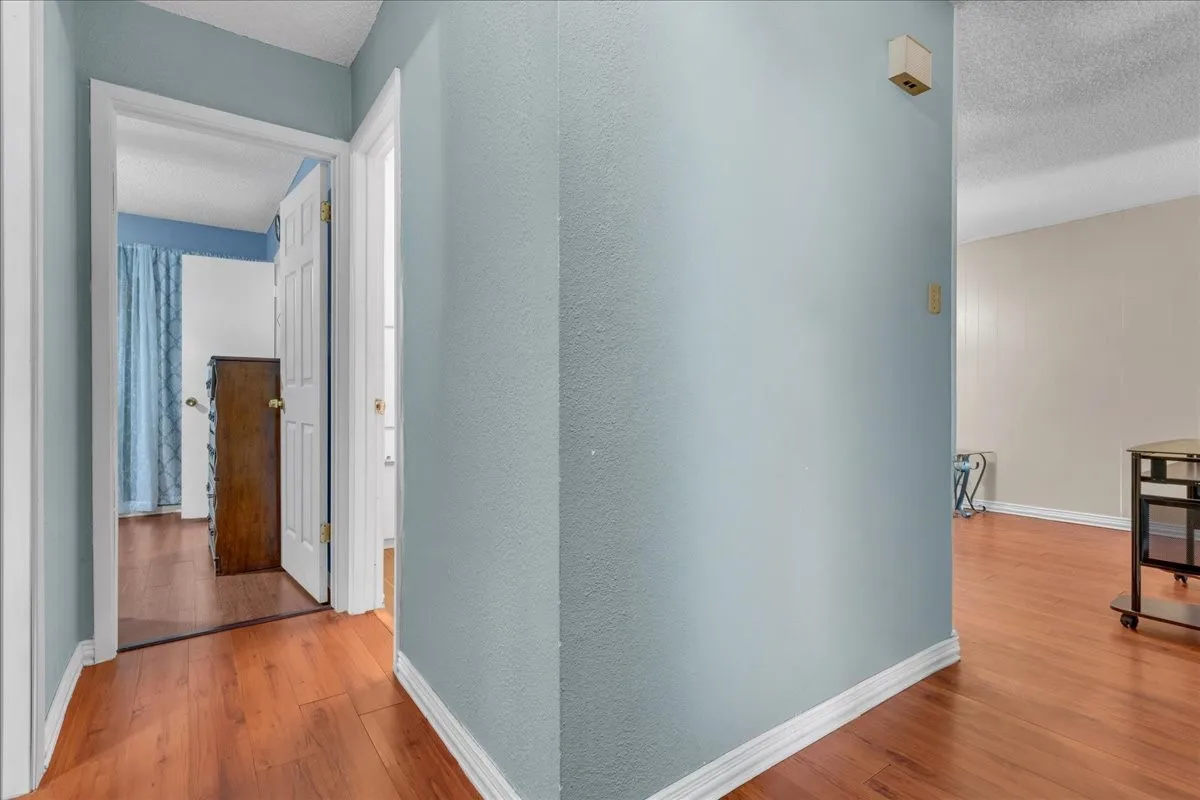Hall featuring light wood-style flooring and a textured ceiling